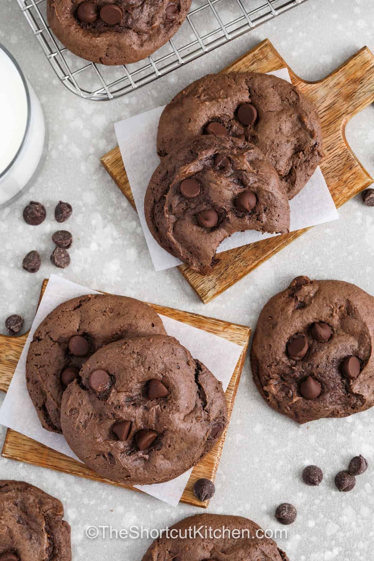 Chocolate cake cookie mix makes these cookies rich, fudgy, and deeply chocolatey with a soft brownie like texture that melts in your mouth. With just a few simple ingredients added in, the dough comes together quickly and bakes into thick, bakery style cookies loaded with chocolate chips in every bite. They are perfect for when you want something homemade without the extra effort or time in the kitchen. #theshortcutkitchen wooden platters with Chocolate Cake Mix Cookies
