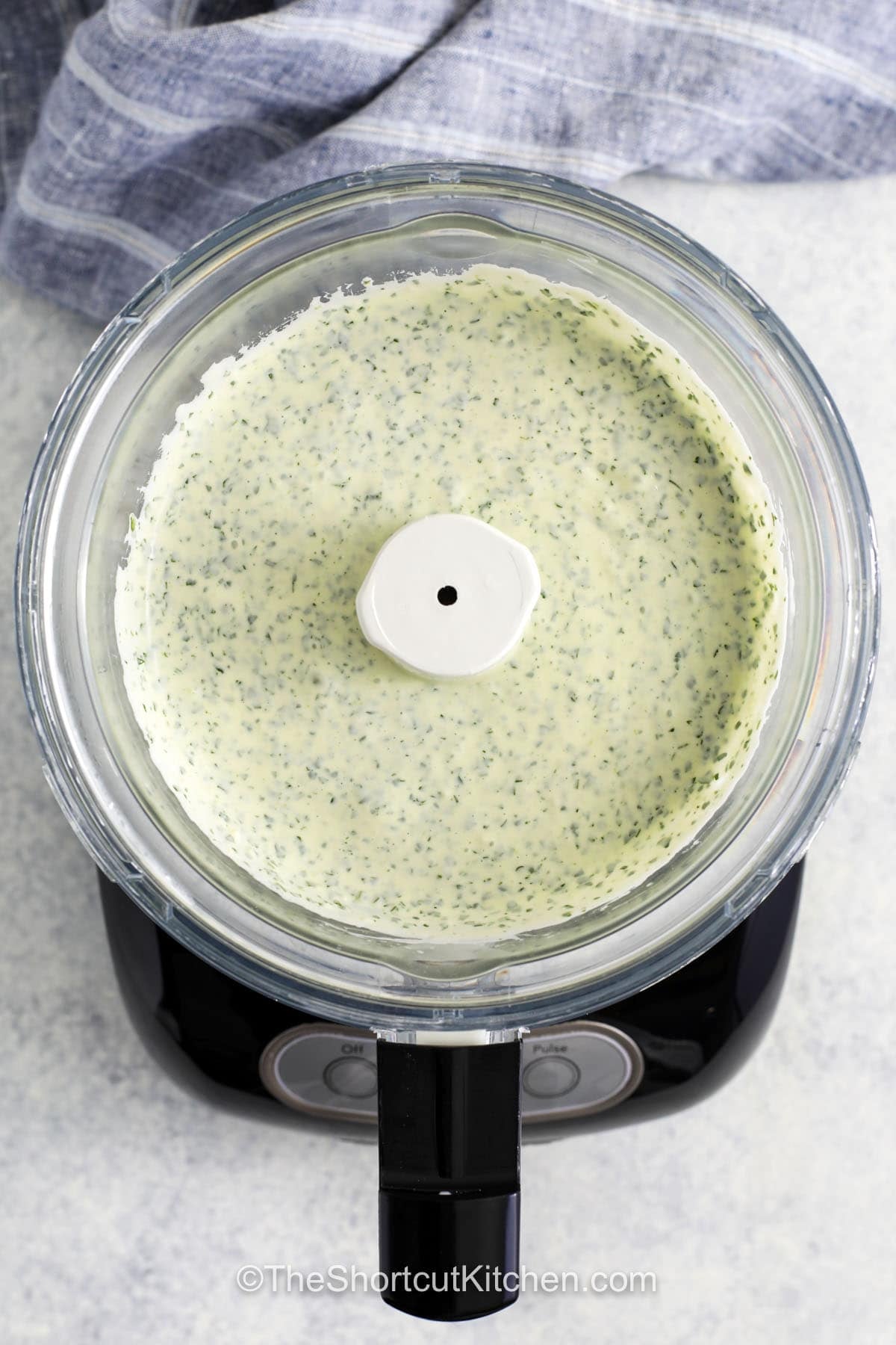 Cilantro garlic sauce is the kind of recipe that makes simple meals and batch cooking better. It combines creamy sour cream, rich mayo, and fresh cilantro with a touch of lime and garlic for zesty flavor. Spoon it over tacos or wraps, bowls, or serve it with roasted vegetables. You can even use it as a dip for chips. This easy sauce adds a fresh twist to everyday cooking. It is a great way to add extra flavor without much effort. #theshortcutkitchen blended Cilantro Garlic Sauce in the food processor