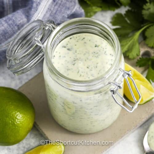 jar of Cilantro Garlic Sauce with limes around it