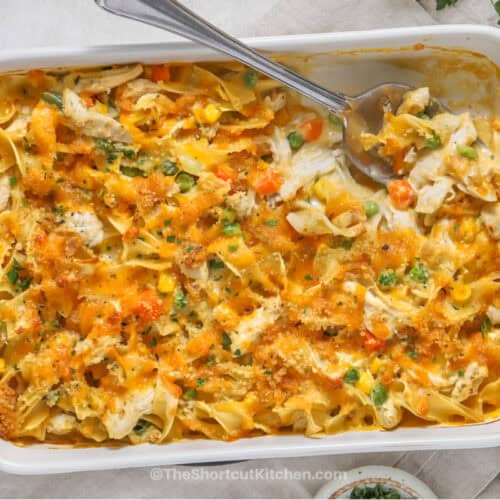 Chicken and noodles casserole prepared in a casserole dish with a spoon in it