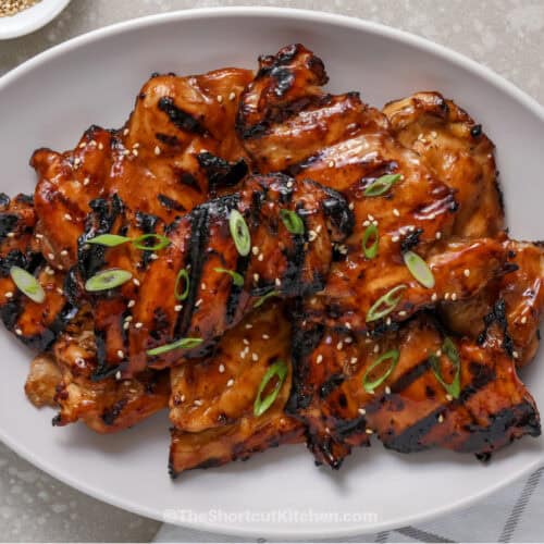 Grilled Teriyaki Chicken on a serving platter topped with sesame seeds and sliced green onions