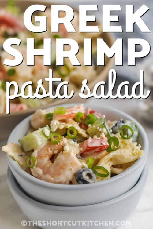 Greek shrimp pasta salad is an easy cold shrimp pasta salad made with tender pasta, cooked shrimp, cucumber, tomatoes, feta cheese, olives, and a creamy Greek dressing. This shortcut-style pasta salad is perfect for summer lunches, potlucks, cookouts, and meal prep. It has fresh Mediterranean-inspired flavor without a lot of work and tastes even better after chilling. #theshortcutkitchen plated Greek Shrimp Pasta Salad with writing
