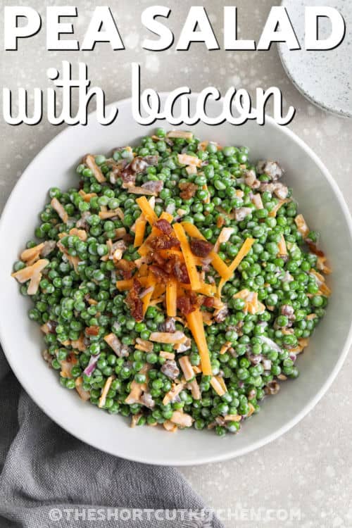 This pea salad with bacon is an easy pea salad recipe made with thawed frozen peas, sharp cheddar cheese, crispy bacon bits, and finely diced red onion in a creamy, tangy dressing. It is the kind of cold side dish that works for spring lunches, holiday dinners, and warm-weather gatherings. If you are looking for a creamy pea salad that is quick, budget-friendly, and full of texture, this one checks every box. #theshortcutkitchen bowl of Pea Salad with Bacon with writing