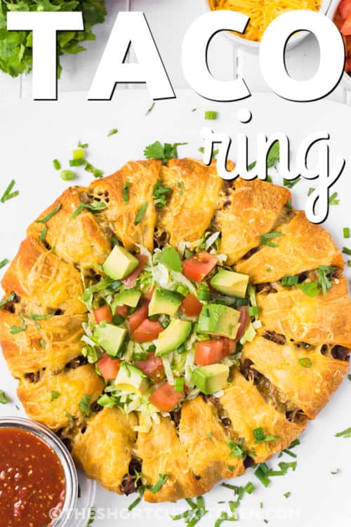 This taco ring recipe is baked comfort food with a fun taco night feel. Ground beef and onion are simmered with taco seasoning, layered with cheddar cheese, and tucked into crescent roll dough before baking. Serve it warm with fresh taco toppings for a simple, flavorful dinner that is easy enough for weeknights and shareable enough for guests. #theshortcutkitchen Taco Ring with avocado and tomatoes and a title