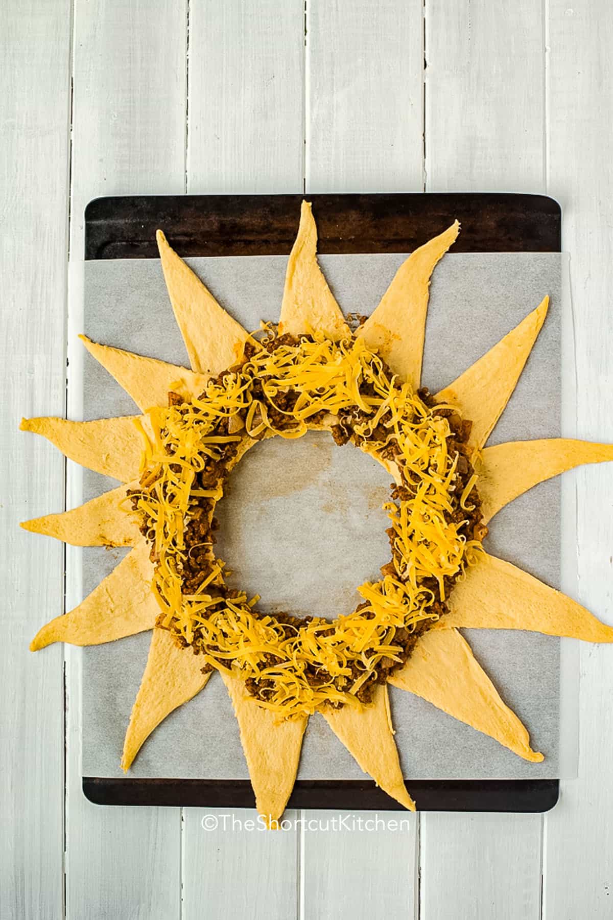 Make this taco ring with crescent rolls for an easy weeknight dinner packed with taco flavor. Ground beef, onion, taco seasoning, and shredded cheese create a hearty filling, while the baked crescent crust turns buttery and golden. Add salsa, lettuce, olives, or avocado in the center for a colorful taco ring recipe everyone can serve themselves. #theshortcutkitchen ground beef and cheese on crescent rolls to make Taco Ring