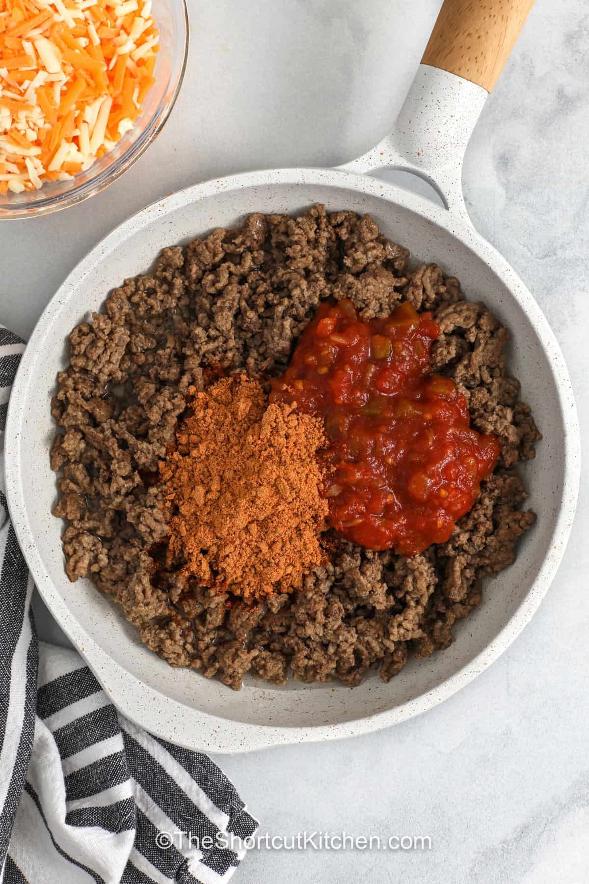 These baked beef tacos are filled with juicy salsa seasoned ground beef and Mexican cheese, then baked until crunchy on the outside and melty inside. Use small flour tortillas for easy folding and serving. This oven baked tacos recipe is a fun way to serve taco night with less mess, simple ingredients, and fresh toppings added after baking. Pin this recipe for an easy taco dinner. #theshortcutkitchen adding taco seasoning and salsa to beef to make Baked Tacos