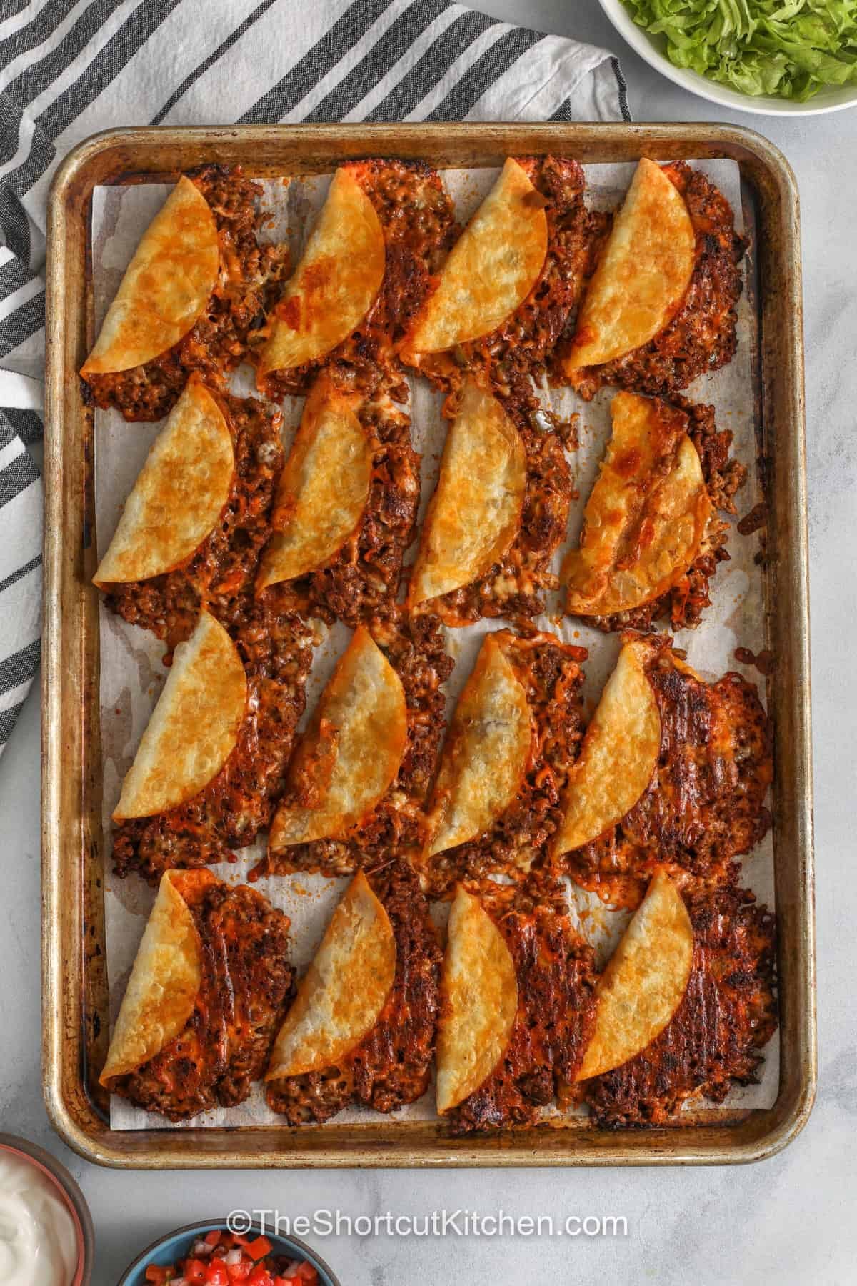 This sheet pan baked tacos recipe turns ground beef, salsa, taco seasoning, tortillas, and cheese into a crispy oven dinner. The hot baking sheet method helps the tacos brown without deep frying, while the filling stays savory and cheesy. These oven baked tacos are great for parties, weeknight meals, and easy leftovers. Pin this crispy taco idea for later. #theshortcutkitchen crispy Baked Tacos on a sheet pan