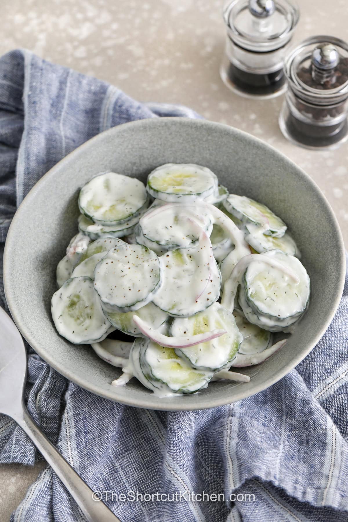 Need a simple side dish for dinner tonight? This creamy cucumber salad recipe is packed with crunchy cucumbers, tangy dressing, and fresh dill flavor in every bite. It is a cold cucumber salad that tastes great with grilled foods, sandwiches, and picnic meals. The creamy dressing coats every slice for a fresh and flavorful side that everyone enjoys. This easy summer salad is great to make ahead and chill before serving. Try this easy cucumber side dish today. #theshortcutkitchen plated Creamy Cucumber Salad Recipe