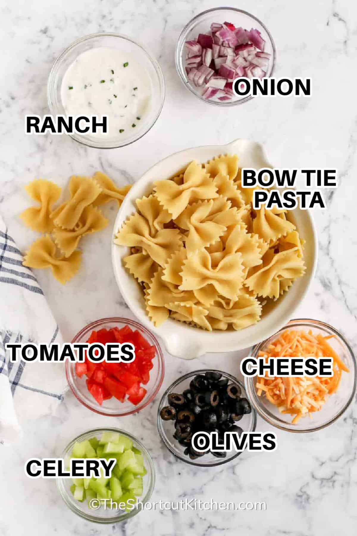 Cold bow tie pasta salad with ranch dressing is a creamy summer side dish that is quick to toss together and easy to make ahead. Tender pasta, cheddar cheese, celery, tomatoes, onion, and olives make every bite flavorful and colorful. Serve chilled with grilled chicken, burgers, sandwiches, or BBQ mains. #theshortcutkitchen ranch , onion , bow tie pasta , cheese , tomatoes , olives , celery with labels to make Bow Tie Pasta Salad