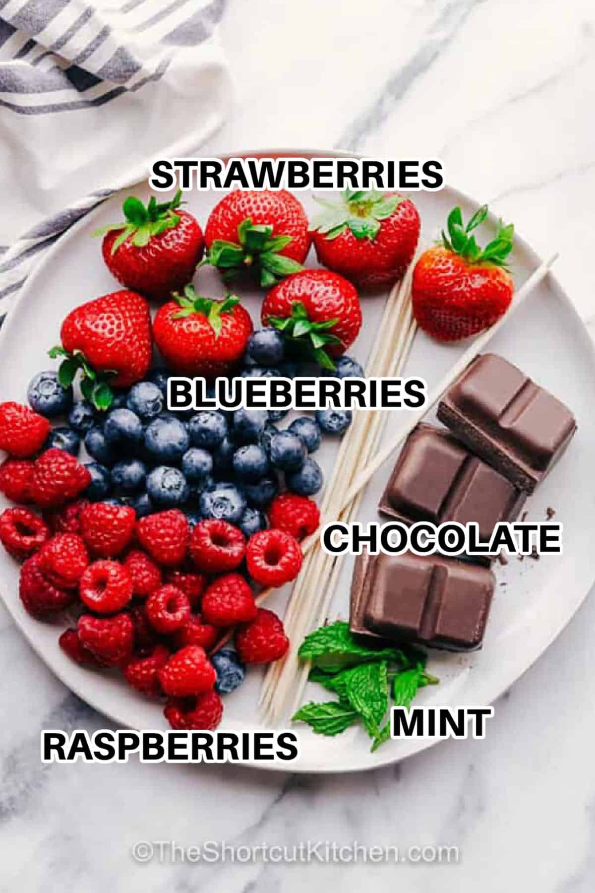 You’ll love making this easy fruit kabob recipe with chocolate and berries. Sliced strawberries are threaded onto skewers with blueberries and raspberries, and then drizzled with melted chocolate. Serve with a dip of strawberry or vanilla yogurt. Explore homemade fruit kabob ideas for kids parties. Why not make a rainbow by adding pineapple, cantaloupe, and honeydew melon? Fruit kabobs make the best wholesome treat that no one can resist. #theshortcutkitchen strawberries , blueberries , raspberries , chocolate , mint with labels to make Fruit Kabobs