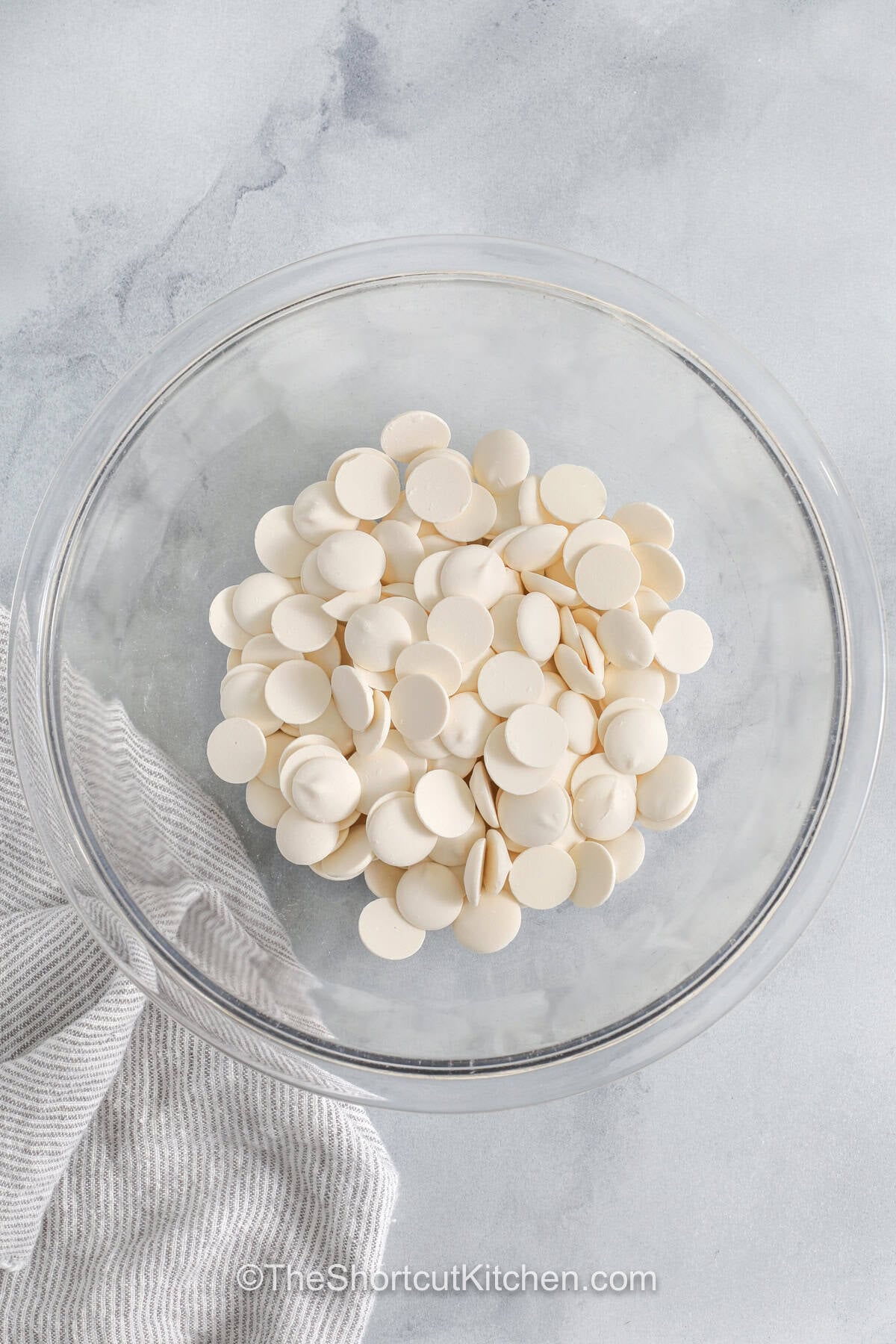 This avalanche cookies recipe combines creamy peanut butter, melted white chocolate, marshmallows, and crispy rice cereal into an irresistible no-bake treat. Every bite has the perfect balance of crunch and chew with a touch of chocolate on top. They are ideal for cookie exchanges, celebrations, or everyday desserts when you want something simple and delicious. Try this recipe and share a batch today. #theshortcutkitchen white candy melts in a bowl to make Avalanche Cookies