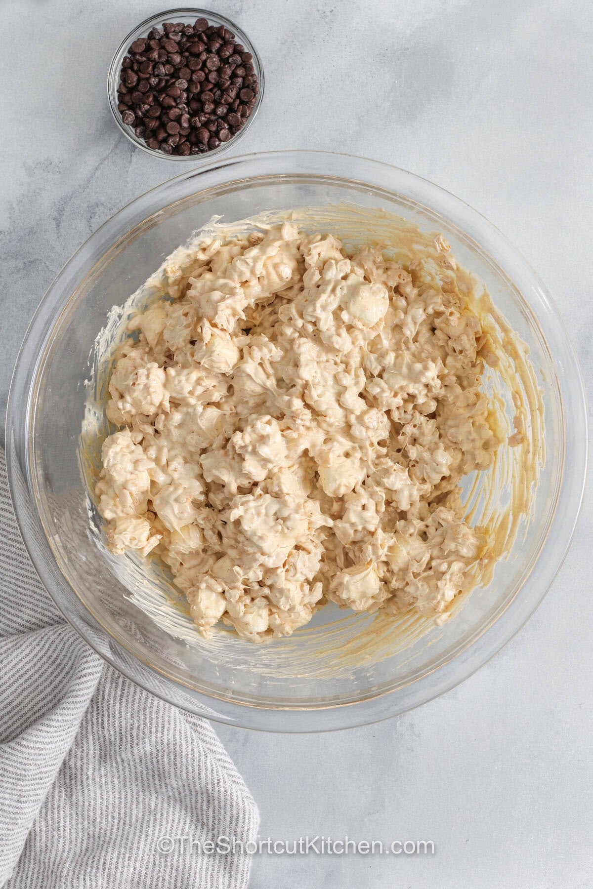 Simple and satisfying, avalanche cookies combine white chocolate, peanut butter, marshmallows, and crunchy cereal into an easy no-bake dessert. Every bite delivers sweetness and texture that makes them perfect for sharing. These cookies are great for holidays, bake sales, or casual snacking at home. They require just a few pantry staples and always turn out delicious. Mix up a batch and enjoy homemade cookies anytime. #theshortcutkitchen mixing ingredients together to make Avalanche Cookies