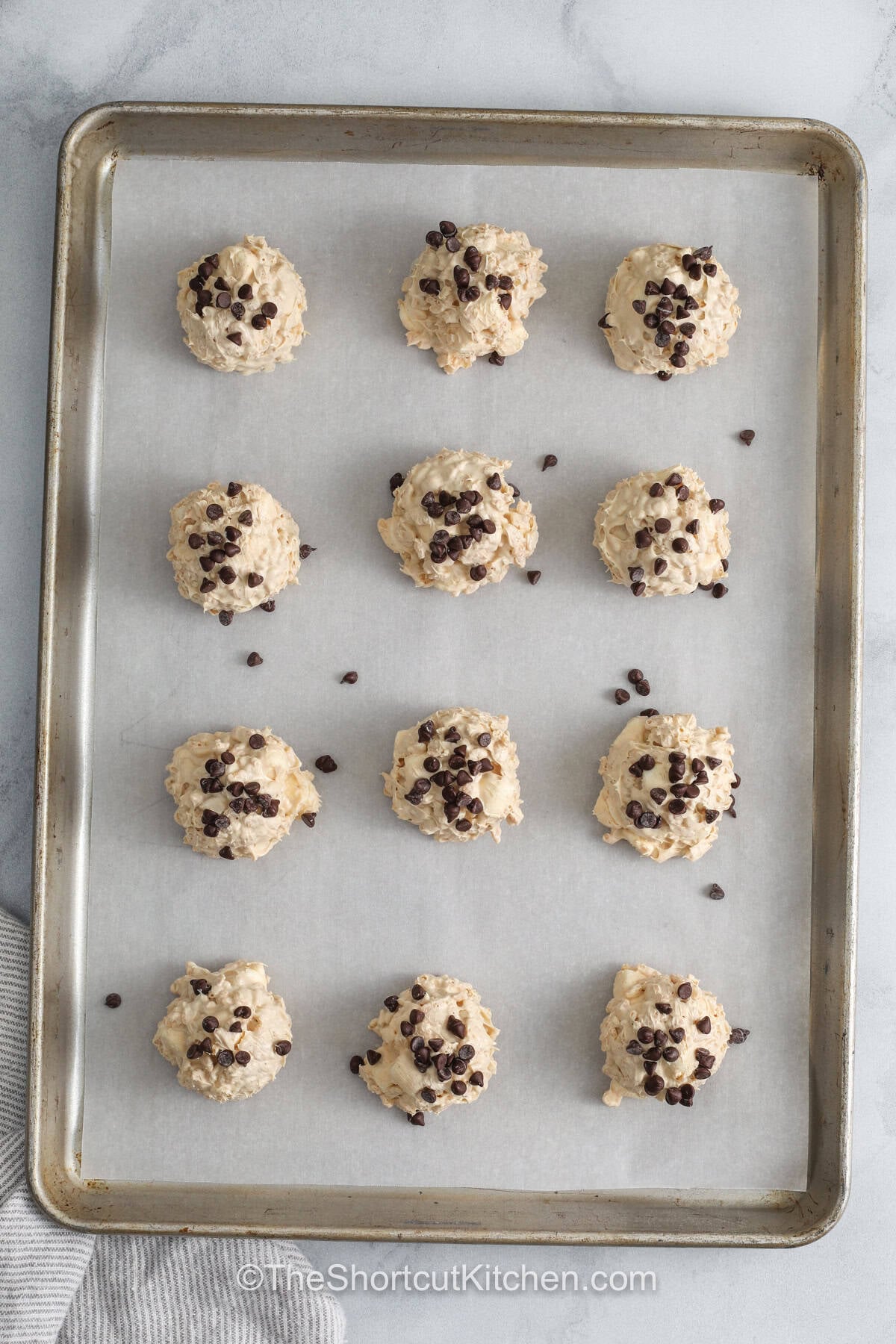Avalanche cookies are the kind of no-bake dessert that feels fun, simple, and packed with sweet flavor in every bite. Creamy peanut butter blends with melted white chocolate, soft marshmallows, and crisp rice cereal for a perfect mix of textures. These cookies are great for quick desserts, lunchbox treats, or party trays. They are easy to prepare and always disappear fast. Make a batch and treat yourself today. #theshortcutkitchen sheet pan with Avalanche Cookies on top