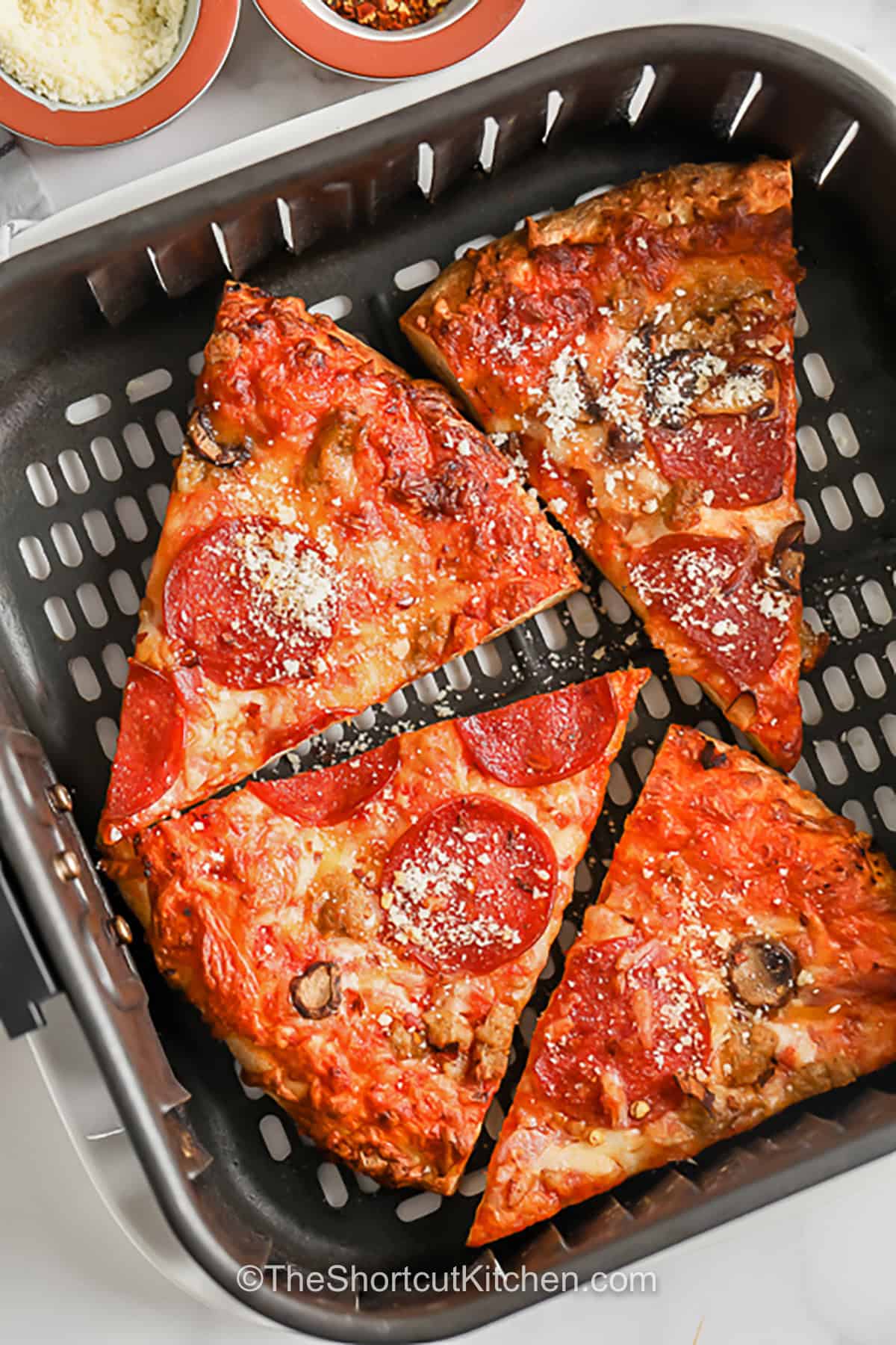 How to reheat pizza in air fryer with simple steps for crispy crust and gooey cheese. This easy leftover pizza method works with cheese pizza, pepperoni pizza, veggie pizza, and pan-style slices. Cook in a single layer for the best texture, then serve with ranch, marinara, or garlic butter. A fast air fryer recipe for pizza night leftovers and quick snacks. Save this method to make leftover pizza taste fresh again. #theshortcutkitchen pepperoni pizza in an air fryer to show How to Reheat Pizza in the Air Fryer