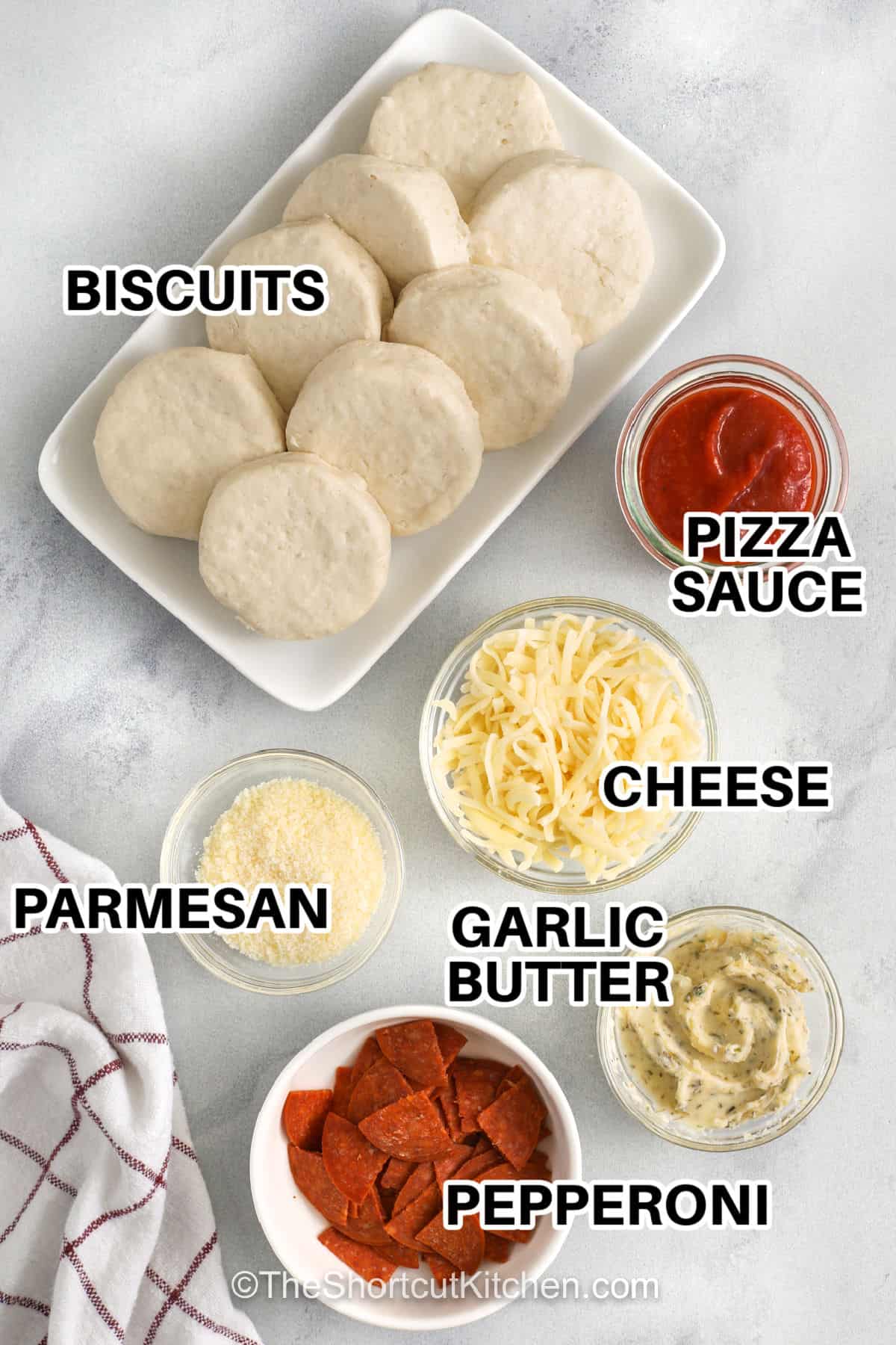 These easy pizza bombs are made with refrigerated biscuit dough, pizza sauce, chopped pepperoni, mozzarella cheese, garlic butter, and parmesan. The biscuits are filled, sealed, baked until golden, and served warm with extra sauce for dipping. This shortcut appetizer is perfect for game day, movie night, after-school snacks, or a fun pizza night recipe. Save this recipe for your next snack night. #theshortcutkitchen pizza bomb ingredients