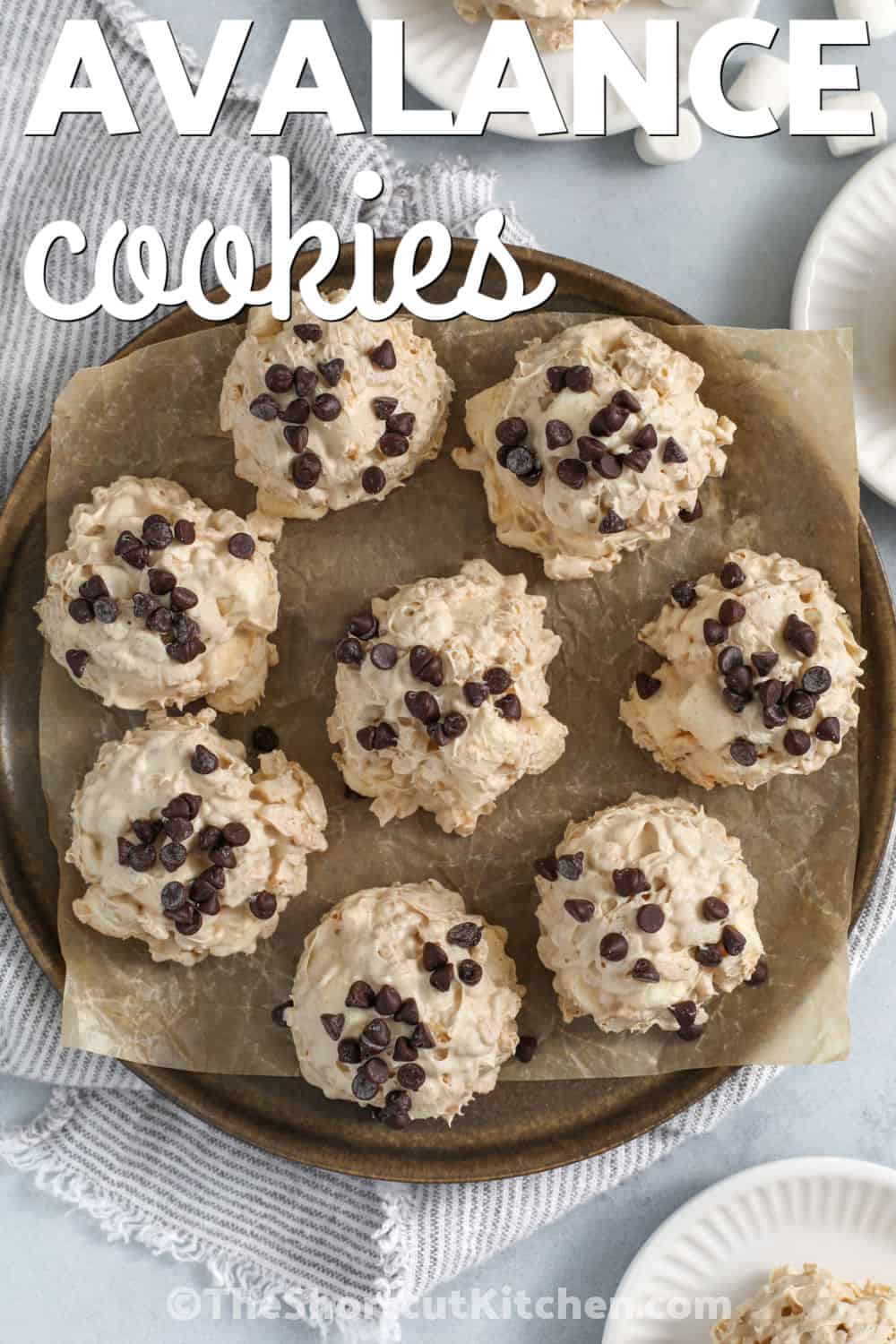 Love avalanche cookies for their sweet flavor, crunchy texture, and easy no-bake preparation. White chocolate and peanut butter coat crispy cereal and fluffy marshmallows to create a dessert everyone enjoys. These homemade cookies are perfect for holiday platters, lunchbox treats, or sharing with friends. They look impressive but come together with everyday ingredients. Give them a try and save this recipe. #theshortcutkitchen plate of Avalanche Cookies with a title