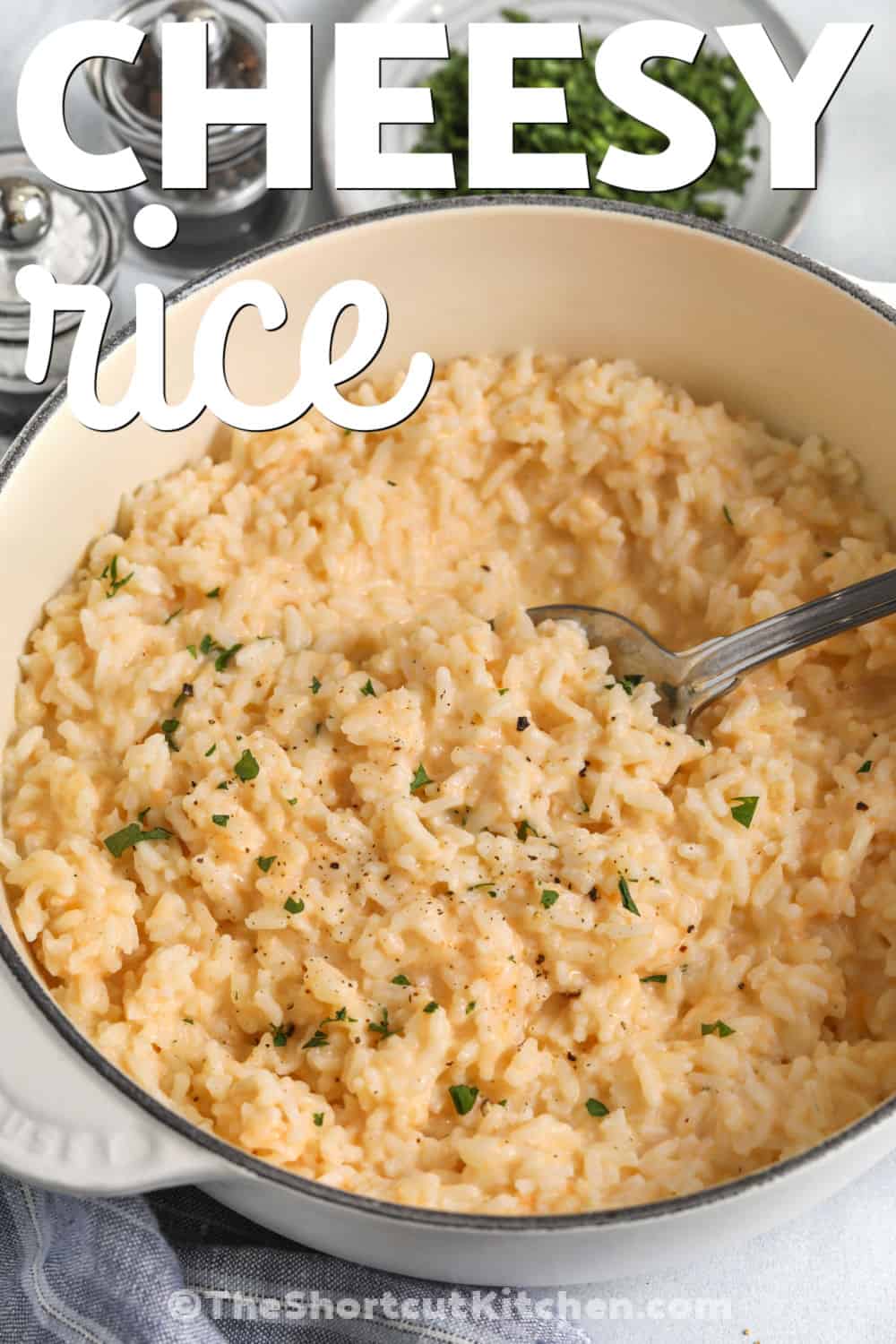 Cheesy rice makes every dinner a little more comforting and satisfying. This easy side dish is made with simple ingredients and has plenty of creamy, cheesy flavor. It pairs perfectly with chicken, pork chops, meatloaf, or grilled steak. Kids and adults both love this family favorite, making it a great choice for busy weeknights or cozy Sunday dinners. Keep this homemade rice recipe on your menu when you need an easy side everyone enjoys. #theshortcutkitchen pot of Cheesy Rice with a spoon and a title