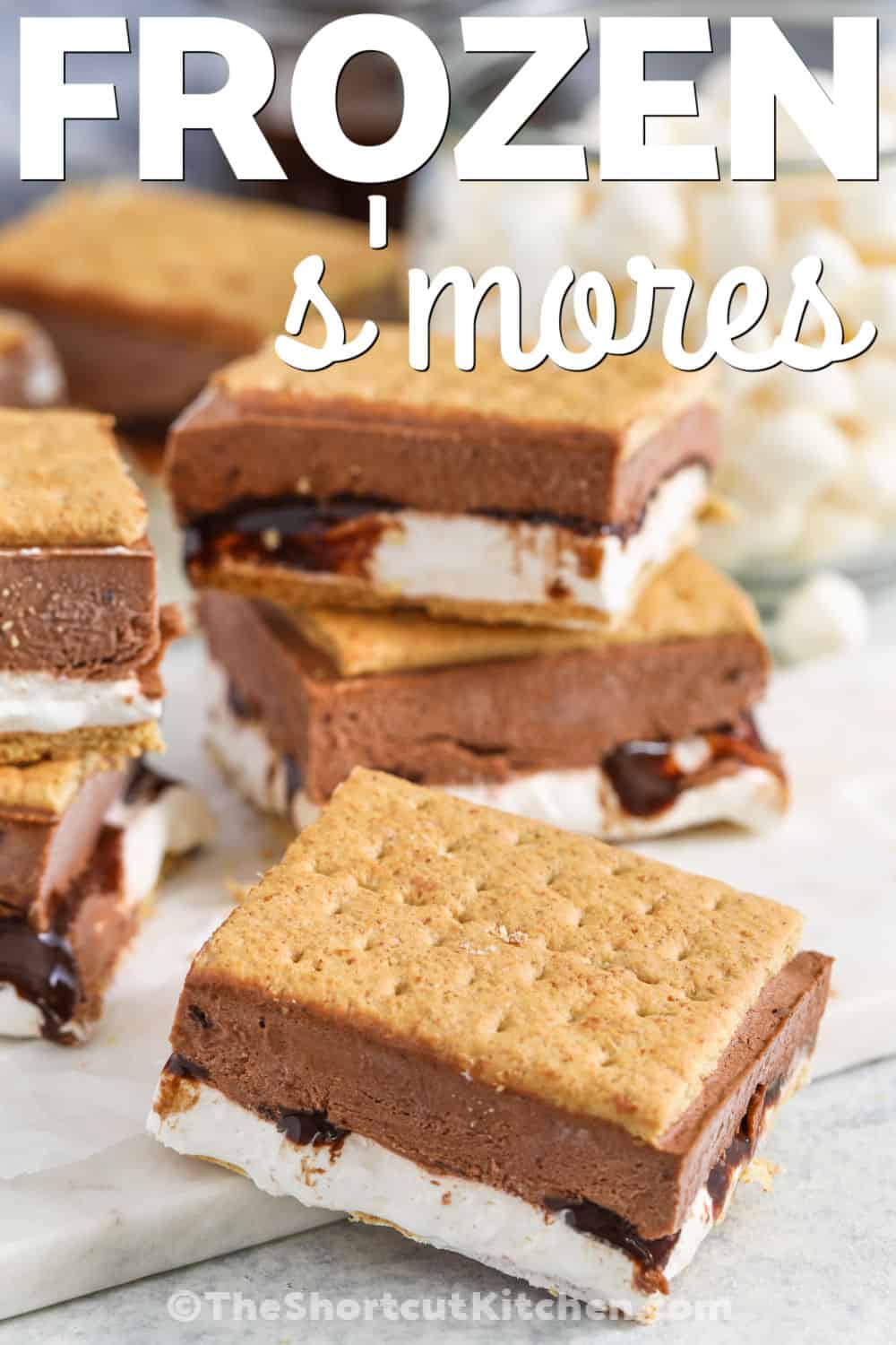 These frozen S’mores bars have all the flavor of classic s’mores without a campfire. Graham crackers sandwich a creamy marshmallow layer, chocolate sauce, and fluffy chocolate pudding filling. This frozen s’mores recipe is simple to prep ahead and perfect for serving straight from the freezer on hot days. Pin it for an easy no-bake treat. #theshortcutkitchen chocolatey Frozen S'mores with writing