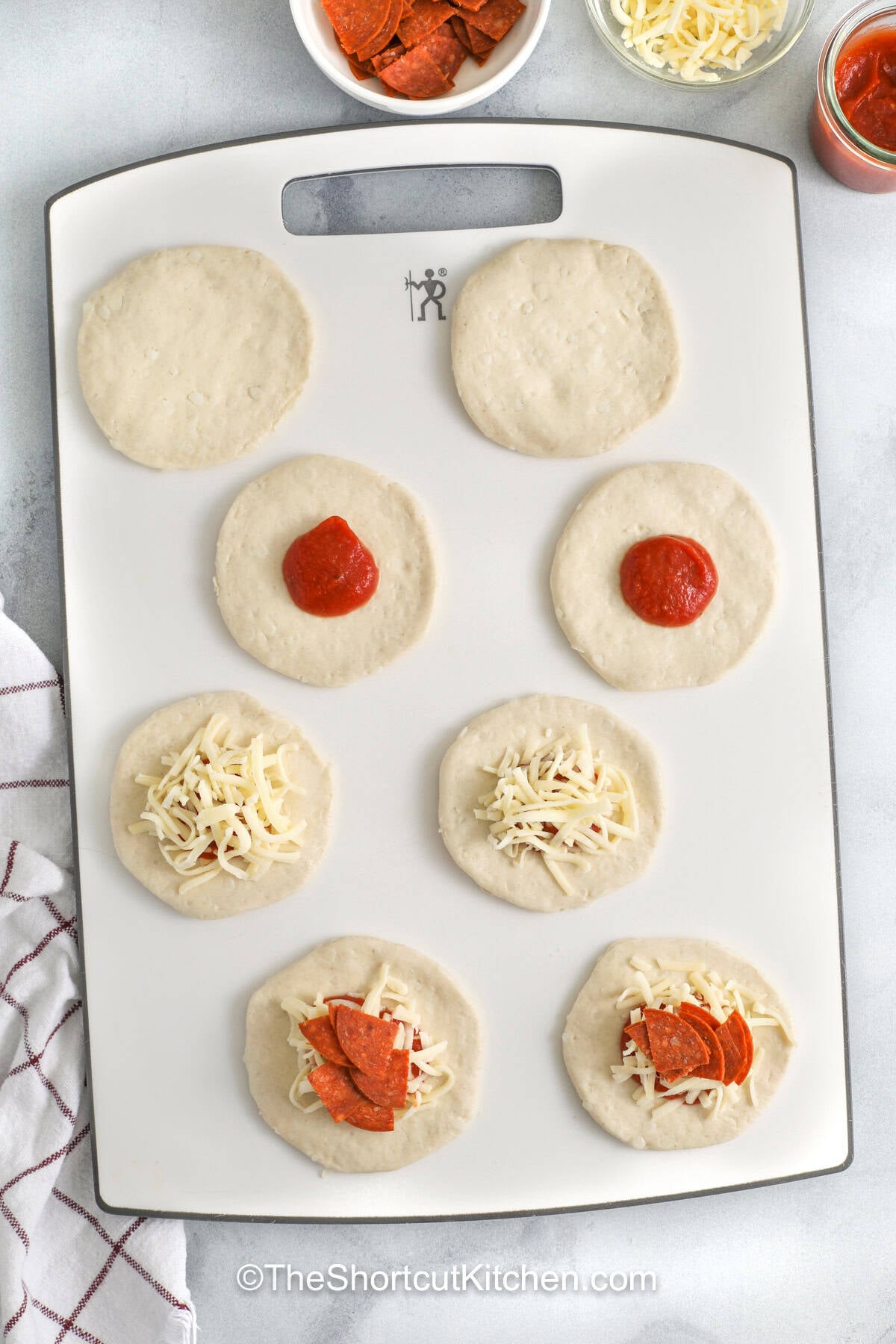 These biscuit pizza bombs are filled with chopped pepperoni, pizza sauce, and mozzarella, then baked until golden and brushed with garlic butter. This easy recipe uses refrigerated biscuits for a shortcut dough that saves time without losing flavor. Add them to a snack board, serve with salad, or make them for a fun Friday night dinner. Pin this for your next easy dinner night. #theshortcutkitchen filling on rolled out pizza dough