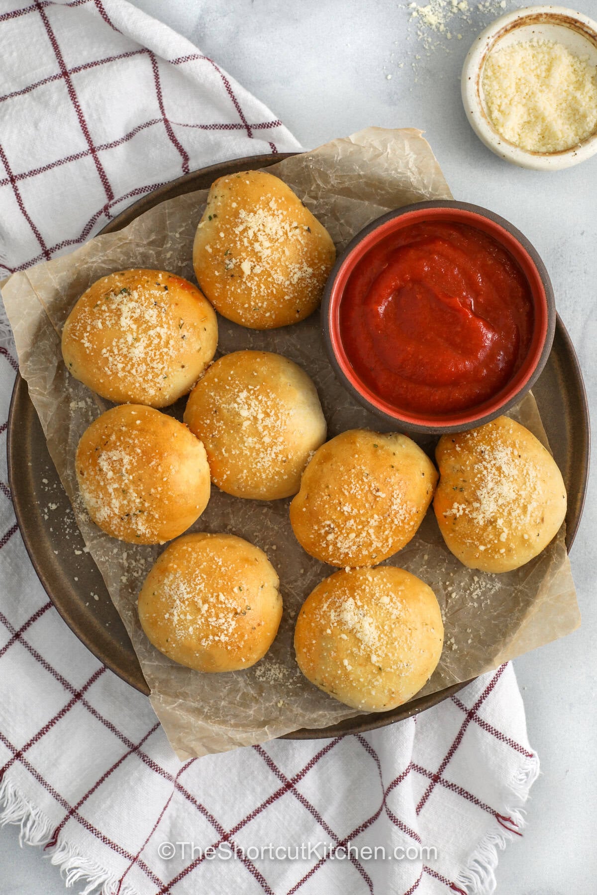 Try this cheesy pizza bombs recipe with canned biscuits for a simple snack that tastes like pepperoni pizza in bite-sized form. The biscuit dough bakes around melty mozzarella and sauce, while garlic butter and parmesan add the perfect finish. Serve warm from the oven with extra pizza sauce for a quick appetizer everyone will love. Save this snack recipe for later. #theshortcutkitchen top view of pizza bombs with dipping sauce