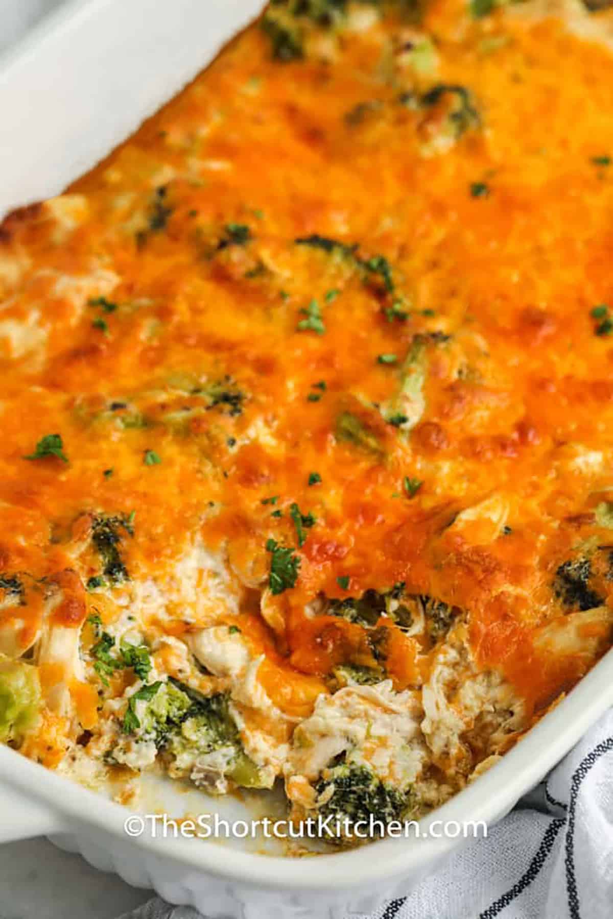 This family-style broccoli chicken casserole layers comforting flavor into every scoop. Tender broccoli and chopped chicken bake in a rich sauce made with cheddar cheese, sour cream, mayonnaise, and condensed mushroom soup. The top becomes melted and golden while the center stays creamy and satisfying. Make it with leftover chicken, turkey, or ham for an easy oven dinner. Pin this chicken and broccoli casserole for your next meal plan. #theshortcutkitchen close up of baked Broccoli Chicken Casserole