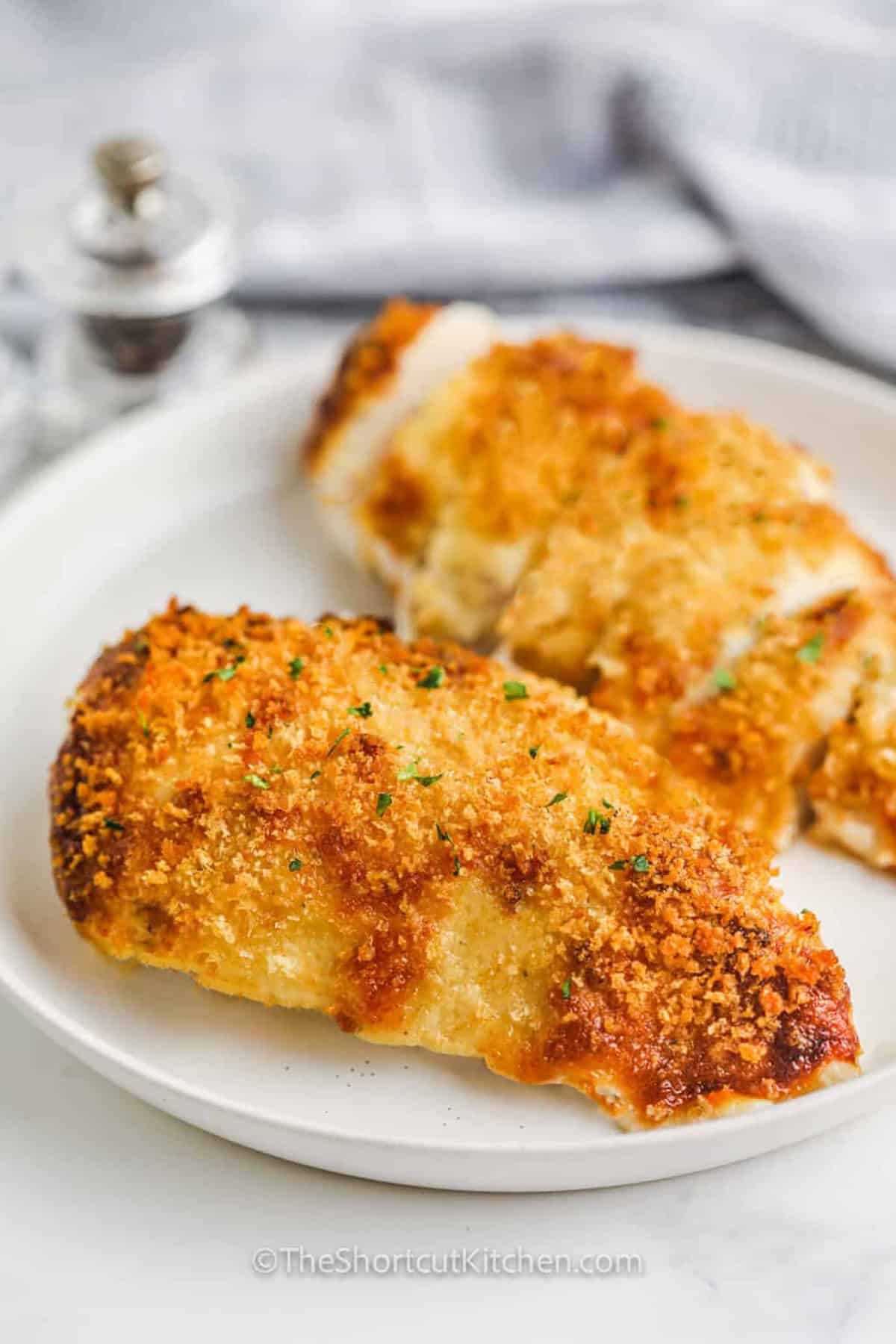 Make parmesan crusted chicken with mayo for a quick family dinner using chicken breasts, ranch mix, Parmesan cheese, and panko bread crumbs. This easy baked chicken recipe has a creamy topping that locks in moisture and creates a golden crust. Pair it with salad, roasted vegetables, rice, or potatoes for a cozy dinner that takes just 35 minutes. Save this easy dinner idea for later. #theshortcutkitchen plated Parmesan Crusted Chicken with Mayo