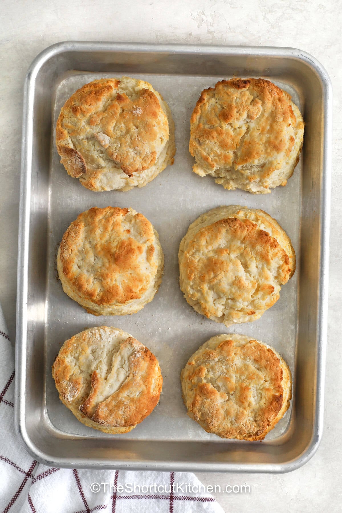 Nothing beats warm biscuits at the table, and 7up biscuits make them simple to prepare. This easy recipe uses Bisquick, sour cream, cold butter, and lemon-lime soda to create fluffy biscuits with a delicious homemade taste. Serve them with butter and jam for breakfast or pair them with soup, chili, or sausage gravy for dinner. They are an easy way to make any meal more inviting. Add 7up biscuits to your recipe list and try them soon. #theshortcutkitchen baked 7up Biscuits on a sheet pan