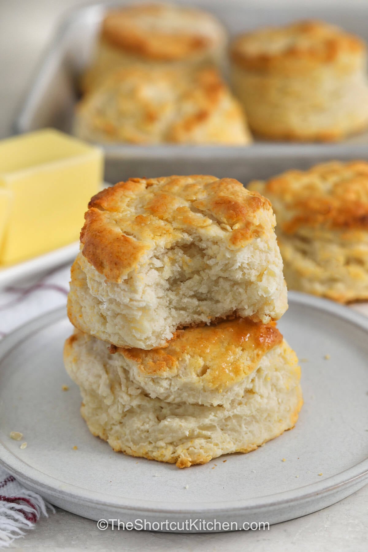 Warm 7up biscuits can turn an everyday meal into something special. This easy biscuit recipe combines Bisquick, sour cream, cold butter, and lemon-lime soda for a simple homemade side. The biscuits are fluffy, buttery, and delicious served with soup, chili, or sausage gravy. They also make a tasty breakfast with butter and jam. If you love easy recipes with simple ingredients, these biscuits belong on your list. Give 7up biscuits a try today. #theshortcutkitchen stack of 7up Biscuits with a bite taken out of one