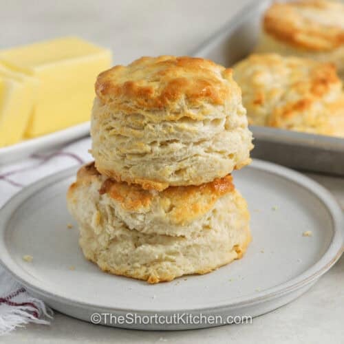 stack of 7up Biscuits on a plate with sheet pan full in the back
