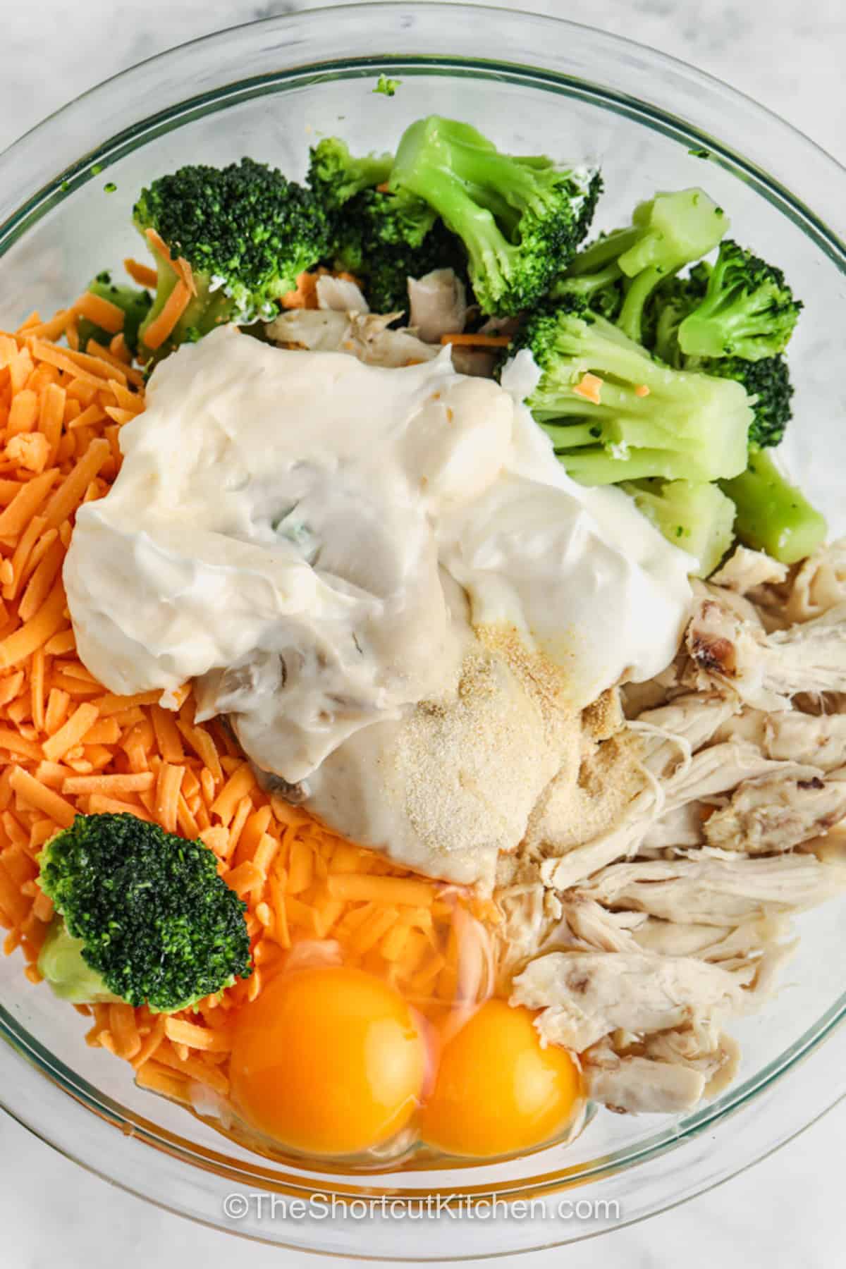 Creamy broccoli chicken casserole is filled with tender chicken, broccoli florets, tangy sour cream, savory mushroom soup, and lots of melted cheddar. Frozen broccoli and precooked chicken make this oven casserole especially quick to prepare. Drain the broccoli well for the best thick, creamy texture, then bake until the top is golden and bubbling. Serve it with salad or rice. Add this casserole to your dinner board. #theshortcutkitchen ingredients in bowl to make Broccoli Chicken Casserole