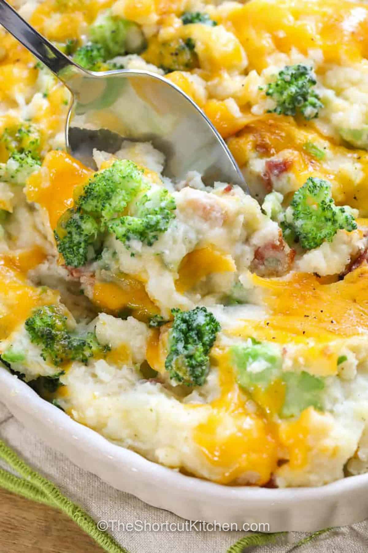 Broccoli potato casserole turns a few everyday ingredients into a rich and satisfying side dish. Fluffy baking potatoes are mashed with cream cheese, sour cream, and butter, then folded with tender broccoli, crisp bacon, sharp cheddar, and Parmesan. Bake this easy broccoli and potato casserole until the cheese topping is hot and bubbly. Save this cozy recipe for family dinners, holidays, and potlucks. #theshortcutkitchen cheesy Broccoli Potato Casserole