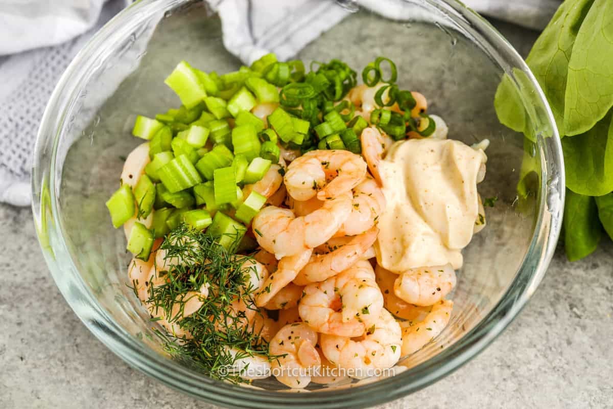 This chilled shrimp salad recipe combines tender cooked shrimp, crisp celery, fresh dill, green onion, and a creamy lemon dressing with Old Bay seasoning. It is quick to prepare, easy to make ahead, and perfect for serving on butter lettuce, crackers, rolls, or croissants. A simple shrimp salad with classic seafood flavor and a fresh, creamy finish. Save this easy seafood recipe for later. #theshortcutkitchen shrimp salad ingredients in a bowl