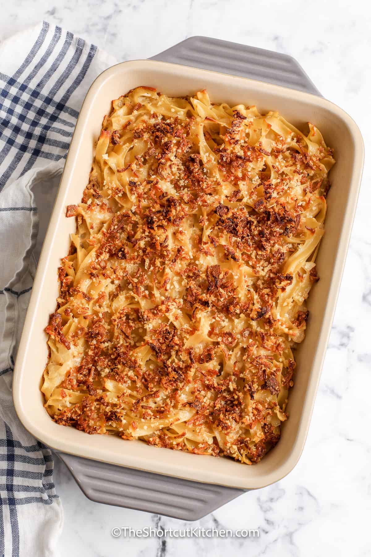 French onion casserole brings the savory flavor of French onion soup to an easy egg noodle bake. Tender noodles are coated in creamy onion sauce and finished with a crisp topping of fried onions, Panko breadcrumbs, Parmesan cheese, and melted butter. This oven-baked casserole serves four and is ready in about 40 minutes. Save this simple recipe for weeknights, potlucks, and cozy family meals. #theshortcutkitchen French Onion Casserole baked in a casserole dish