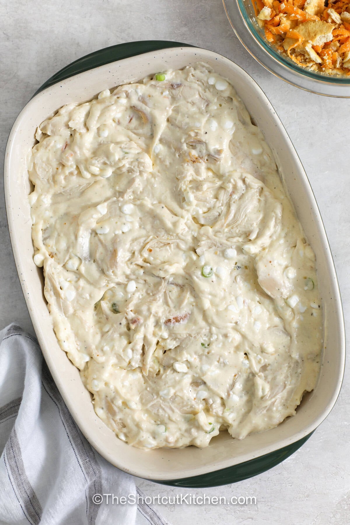 Million dollar chicken casserole brings creamy, cheesy goodness to the dinner table. This easy chicken casserole recipe combines tender chicken with a flavorful filling and golden cracker topping for a meal that feels special. It is a great way to use leftover or rotisserie chicken while creating a family favorite. Save this recipe and try it for your next cozy meal. #theshortcutkitchen adding Million Dollar Chicken Casserole ingredients to casserole dish