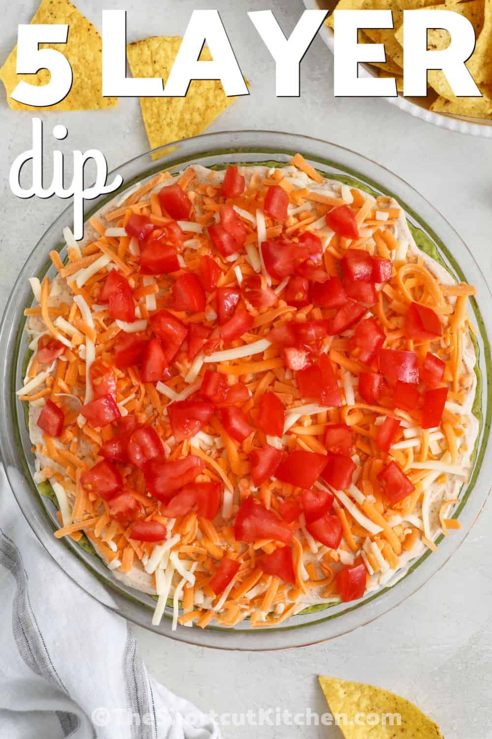5 layer dip brings together fresh layers of flavor that make every scoop worth reaching for. This easy Mexican dip combines creamy, cheesy, and zesty ingredients into a party appetizer everyone enjoys. It is a great choice for potlucks, holiday gatherings, game day spreads, or casual family snacks. Give this favorite a spot on your table and enjoy every delicious bite. #theshortcutkitchen 5 Layer Dip in a glass dish with a title