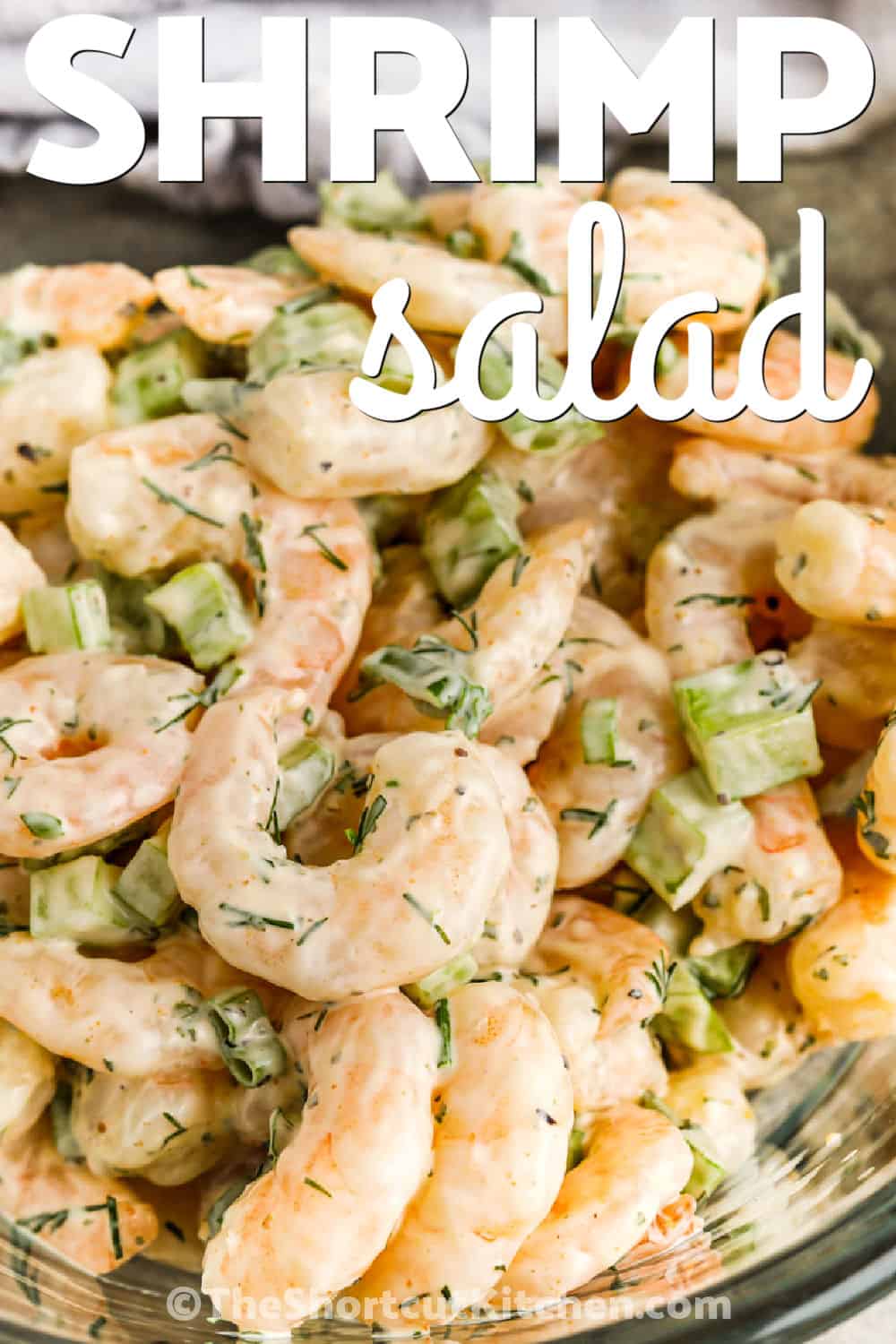 Shrimp salad is an easy no-cook seafood recipe made with cooked shrimp, mayonnaise, lemon juice, celery, green onion, dill, and Old Bay. The shrimp salad chills for one hour so the dressing flavors the shrimp and stays cool and creamy. Serve it on butter lettuce for a light meal, spoon it into rolls, or pair it with crackers for entertaining. Pin this easy shrimp recipe for later. #theshortcutkitchen close up of Shrimp Salad in a bowl with a title