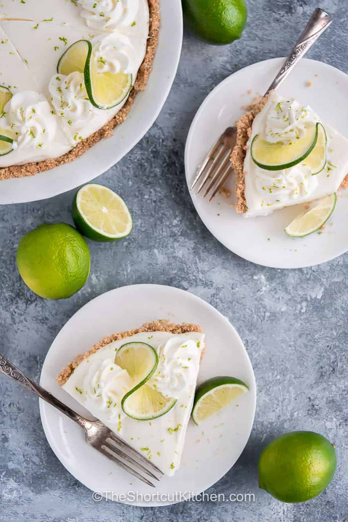 Skip the oven and make this creamy no bake key lime pie instead. Fresh lime flavor, homemade whipped cream, and an easy graham cracker crust come together for a refreshing dessert that's always a hit. The light, fluffy filling sets beautifully in the refrigerator for effortless serving. Save this recipe for your next celebration. #theshortcutkitchen slices of No Bake Key Lime Pie on plates