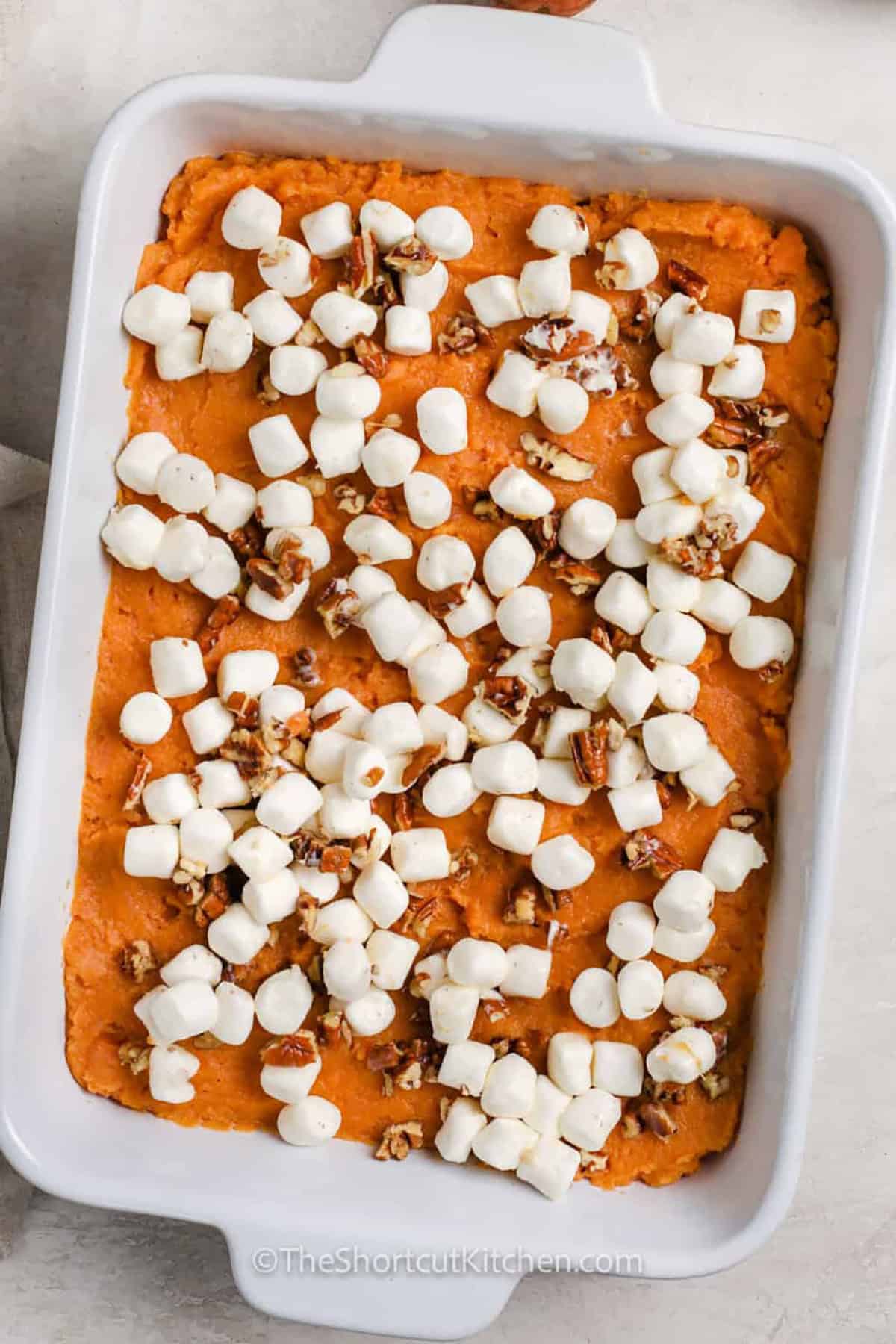 Make canned sweet potato casserole for a classic Thanksgiving side without all the prep. Canned sweet potatoes are drained, mashed, and mixed with cream, butter, brown sugar, egg, and cinnamon, then topped with mini marshmallows and pecans. The oven does the rest in about 20 minutes. Creamy underneath and toasted on top, this easy canned yams casserole is holiday comfort food made simple. Pin the recipe for later. #theshortcutkitchen Canned Sweet Potato Casserole before baking.