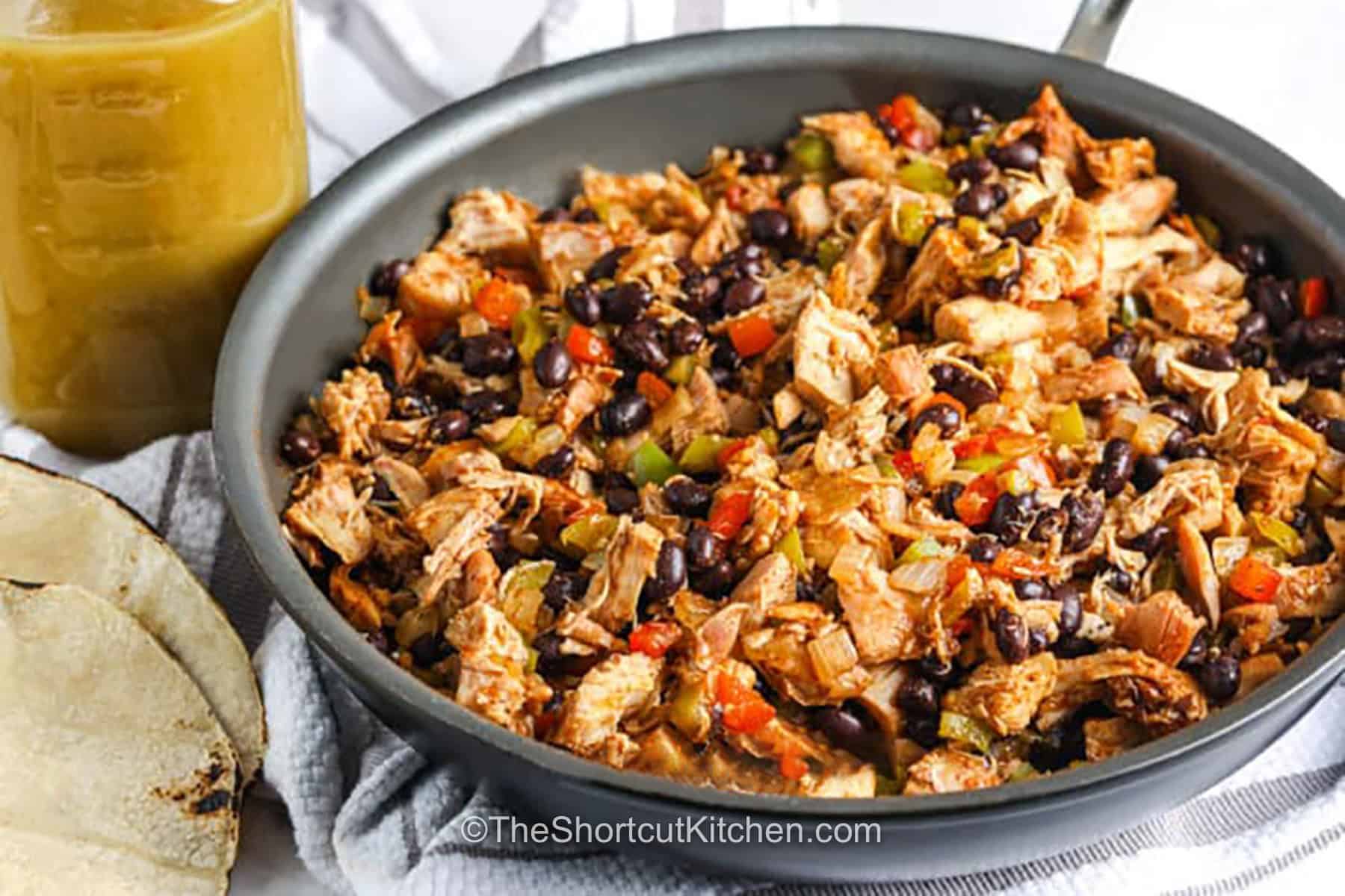 Looking for an easy Mexican-inspired dinner? This chicken enchilada casserole delivers creamy, cheesy comfort with simple ingredients and very little prep. Layer everything together, bake until bubbly, and enjoy an easy meal that's perfect for weeknights. Save this recipe today. #theshortcutkitchen cooking Chicken Enchilada Casserole filling in a pan.