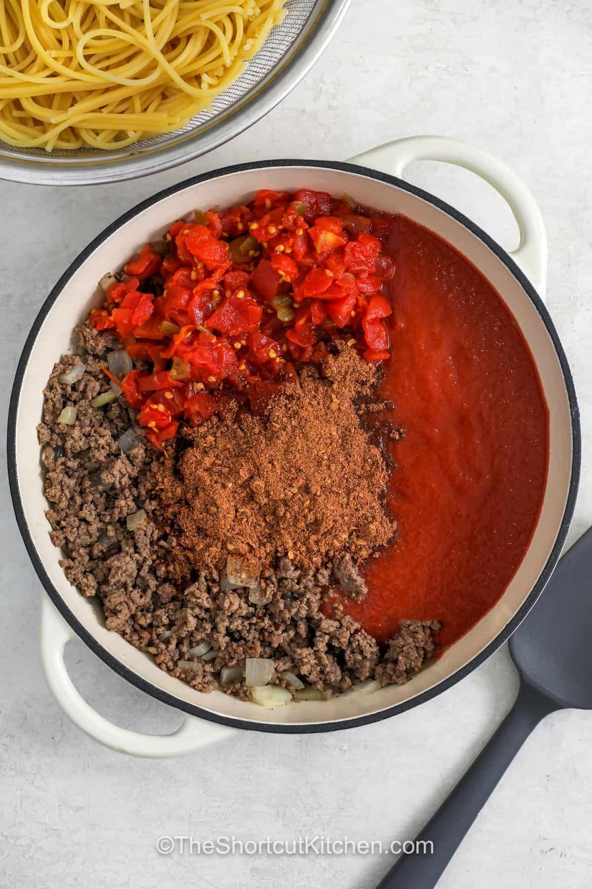 Craving comfort food? Cowboy spaghetti combines ground beef, spaghetti, tomato sauce, and chili-seasoned tomatoes. The hearty sauce coats every strand of pasta, while cheddar cheese, bacon bits, and green onions make tasty toppings. This easy pasta dinner is filling, flavorful, and family-friendly. Give it a try tonight. #theshortcutkitchen adding ingredients together to make meat sauce for Cowboy Spaghetti