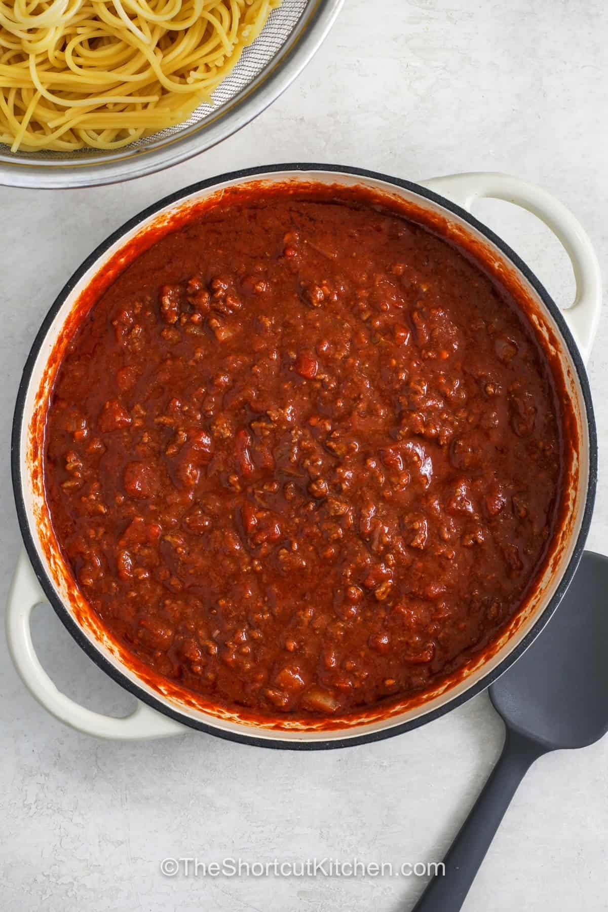 Cowboy spaghetti brings together tender pasta, seasoned ground beef, and zesty tomatoes in one hearty dinner. A packet of chili seasoning adds bold flavor to the savory tomato sauce without a long list of spices. Add shredded cheddar, crispy bacon bits, and green onions before serving. Try this easy family dinner tonight. #theshortcutkitchen meat sauce to make Cowboy Spaghetti