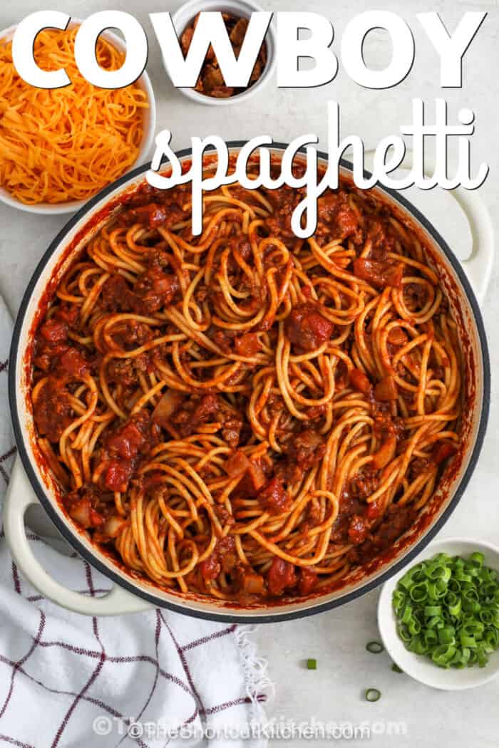 cowboy spaghetti in the pot with toppings in the background and a title