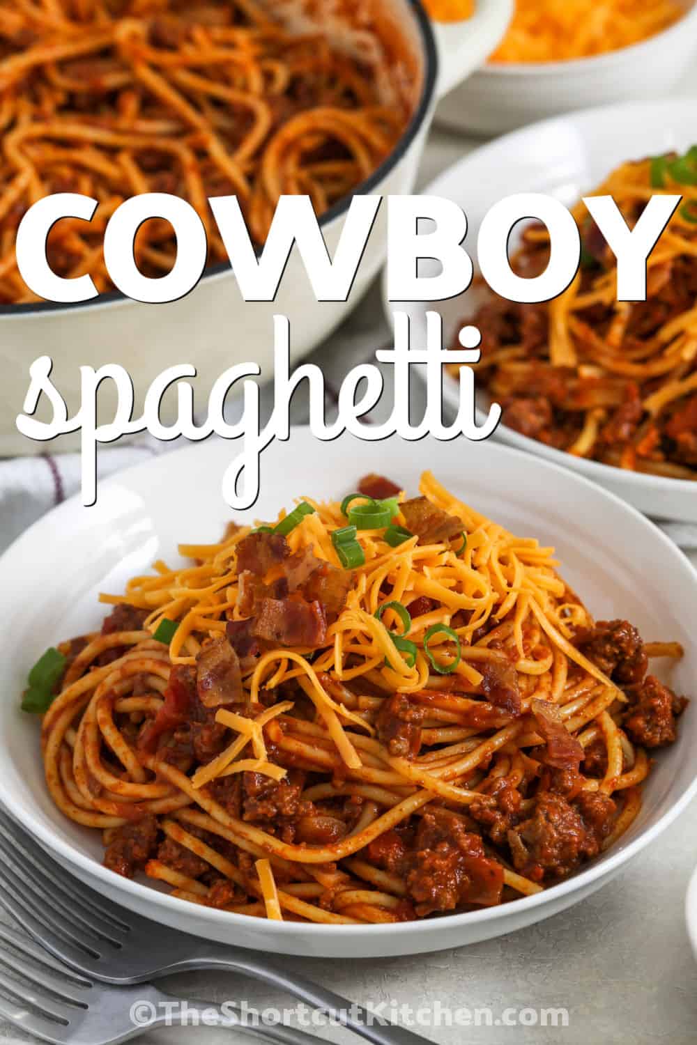 Cowboy spaghetti is a hearty pasta dinner loaded with ground beef, tomato sauce, and chili-seasoned flavor. Tender spaghetti is tossed with a rich beef sauce and diced tomatoes with chilies for a family-friendly meal. Top each serving with cheddar, bacon bits, and green onions for extra flavor. Make this easy comfort food tonight. #theshortcutkitchen cowboy spaghetti in a bowl with a title