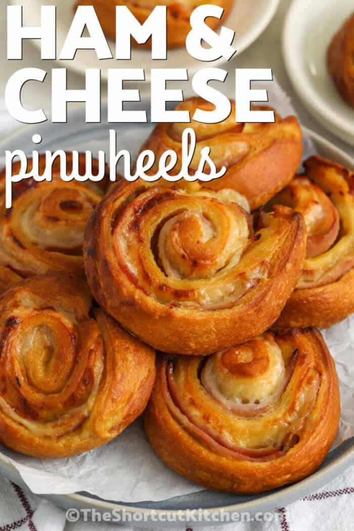 closeup of ham and cheese pinwheels on a platter with a title