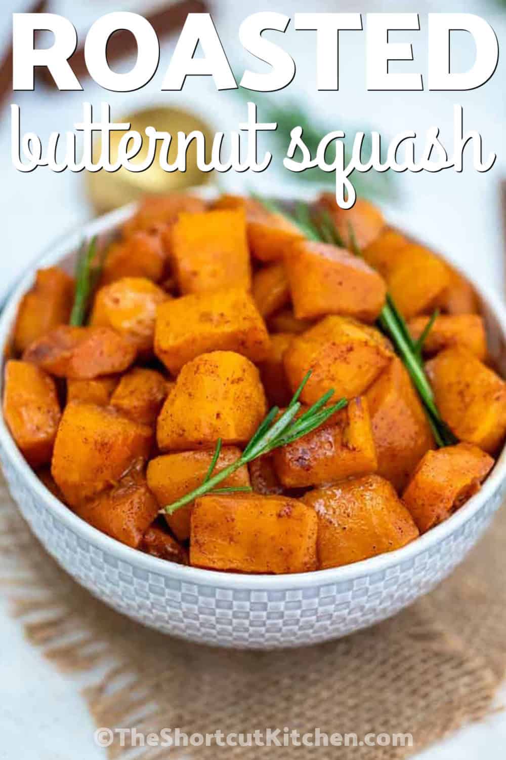Make oven roasted butternut squash with maple syrup and cinnamon for a cozy side that works for weeknight dinners and holiday meals. Cubed butternut squash is coated with olive oil, maple, warm spices, and optional brown sugar before roasting until tender and caramelized. Fresh rosemary gives the sweet roasted butternut squash a savory finish. Pin this easy roasted vegetable recipe for later. #theshortcutkitchen delicious Oven Roasted Butternut Squash with writing