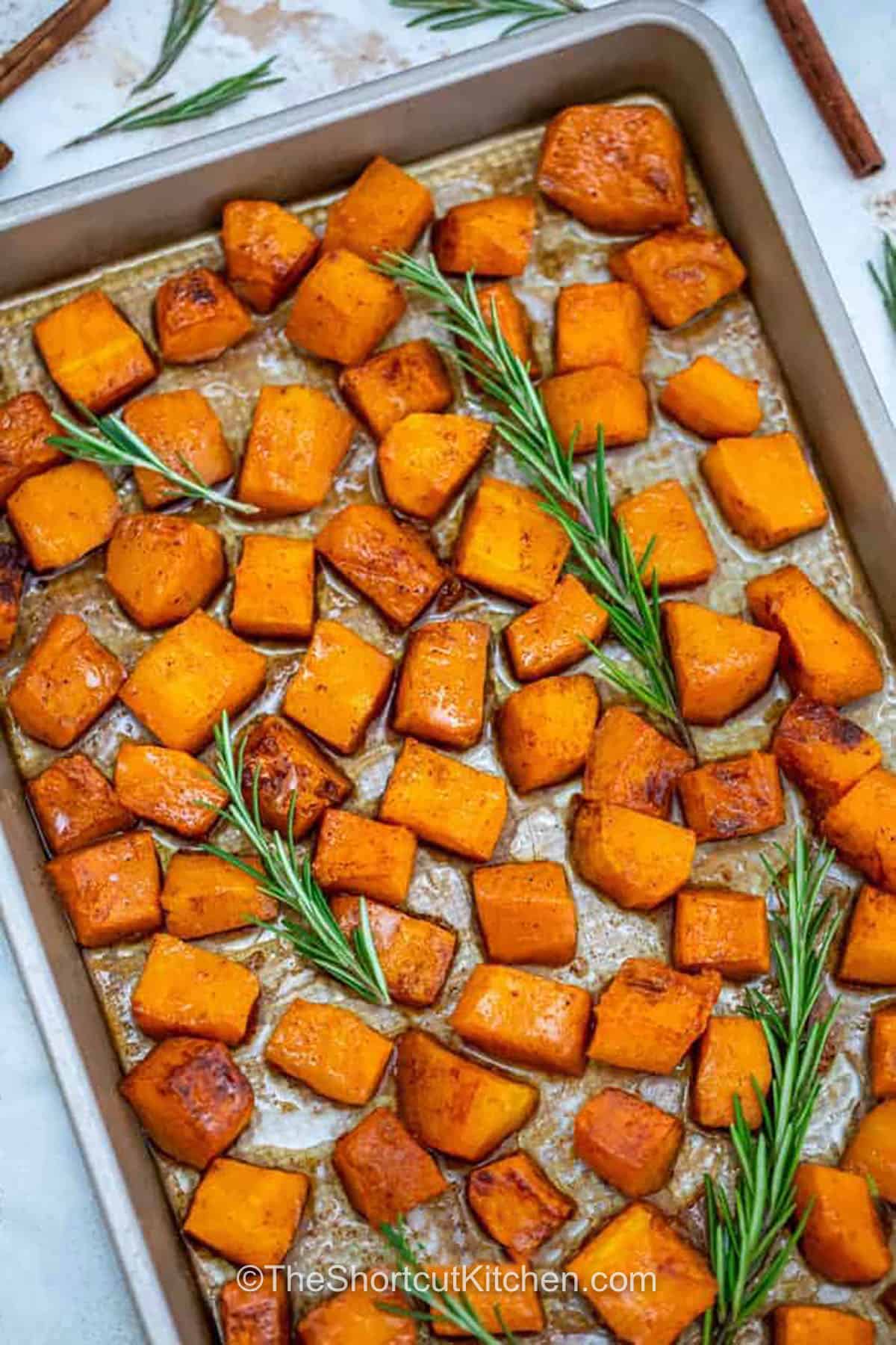 Maple oven roasted butternut squash has tender centers, golden edges, and plenty of cozy fall flavor. Toss butternut squash cubes with olive oil, pure maple syrup, cinnamon, nutmeg, and optional brown sugar, then oven roast until caramelized. Finish with fresh rosemary for a savory contrast. This simple sheet-pan side pairs beautifully with chicken, pork, turkey, or ham. Pin this easy fall side today. #theshortcutkitchen sheet pan with savory Oven Roasted Butternut Squash