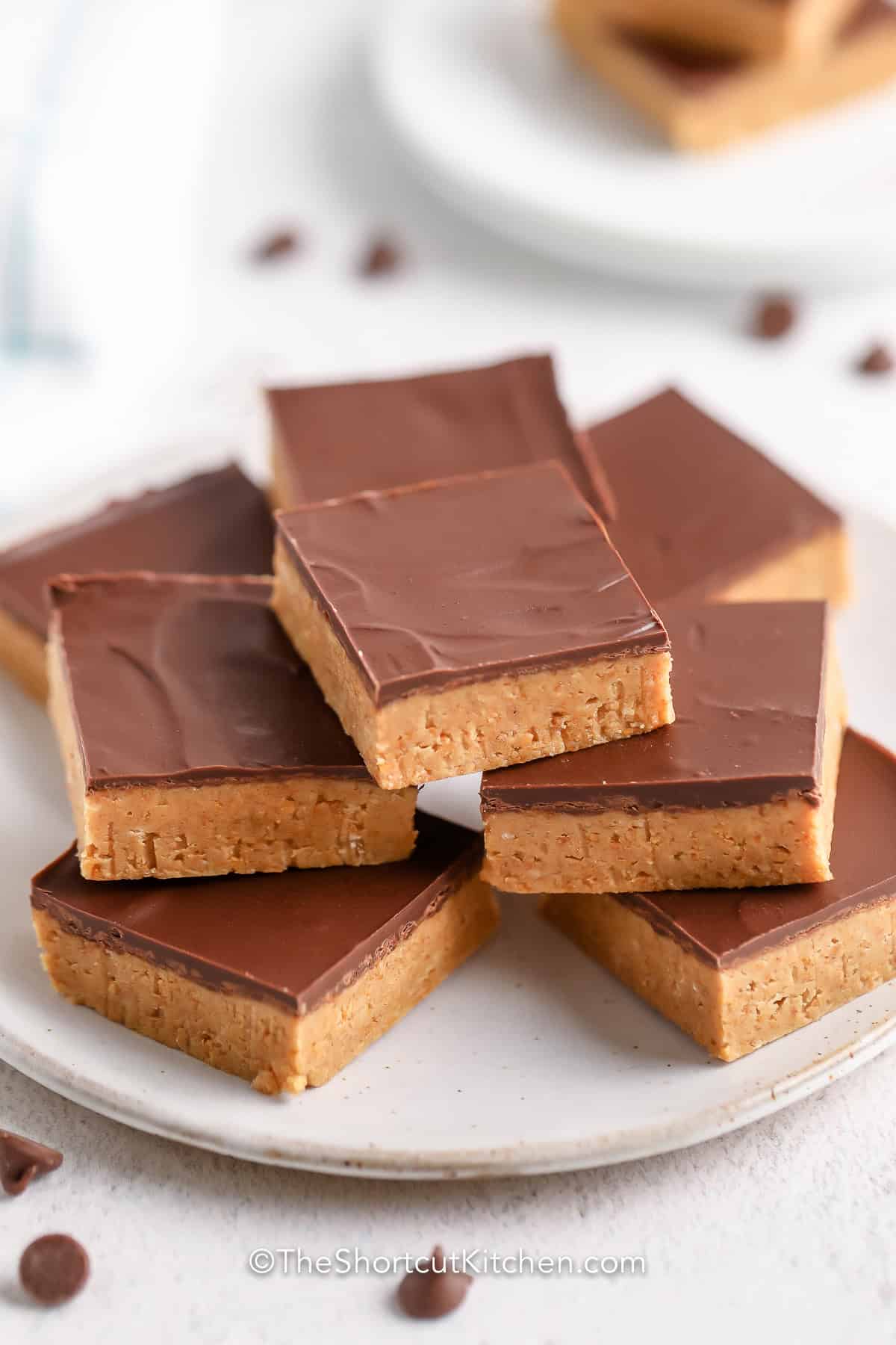 These easy peanut butter bars recipe deliver rich peanut butter flavor, creamy texture, and a smooth chocolate finish without turning on the oven. Great for holidays, potlucks, and meal prep desserts since they freeze beautifully. Save this recipe for your dessert collection. #theshortcutkitchen plated Peanut Butter Bars