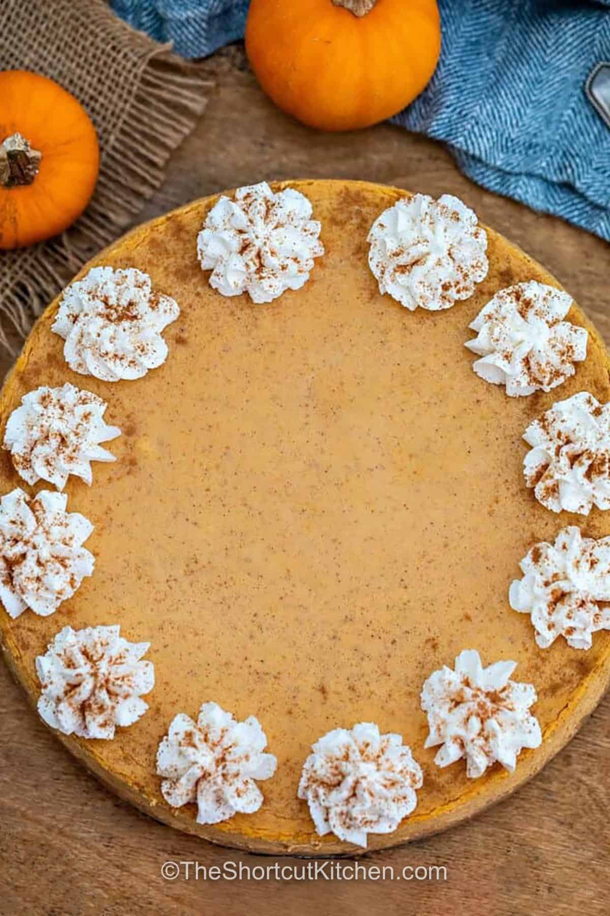Pumpkin pie cheesecake turns classic fall flavors into a rich make-ahead dessert. Cream cheese, pumpkin pie filling, sour cream, and pumpkin spice create a smooth cheesecake filling, while graham cracker crumbs make an easy buttery crust. Bake it gently in a water bath, chill until firm, then finish with whipped cream and caramel. Save this creamy pumpkin cheesecake for your next fall gathering. #theshortcutkitchen Pumpkin Pie Cheesecake with whipped cream