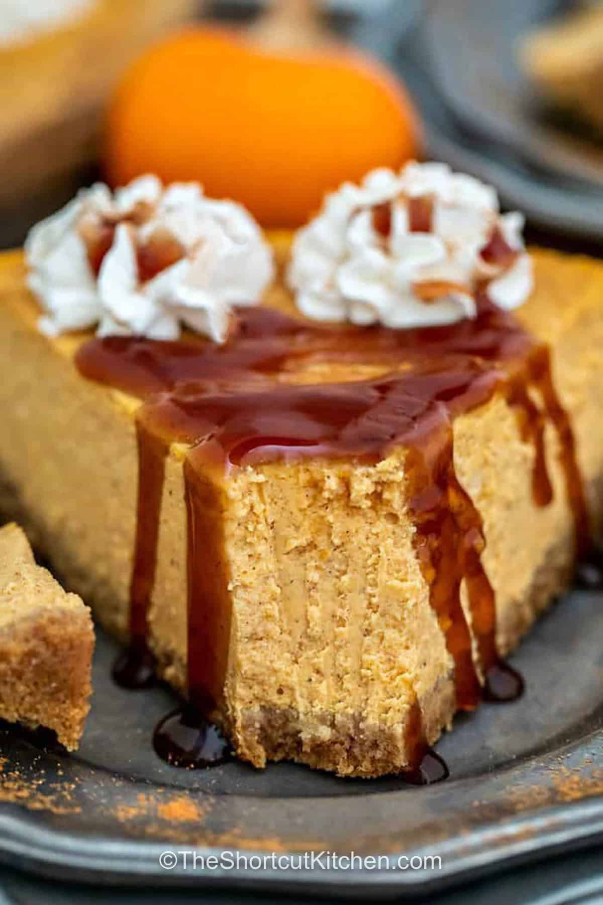 Make pumpkin pie cheesecake when pumpkin pie and cheesecake both sound too good to skip. Cream cheese, pumpkin pie filling, sour cream, and warm spice create a silky baked filling over a buttery graham cracker crust. Fresh whipped cream and optional caramel give this fall cheesecake a festive finish that is perfect for Thanksgiving. Pin this creamy cheesecake recipe for your holiday dessert menu. #theshortcutkitchen Pumpkin Pie Cheesecake with chocolate sauce and whipped cream on top
