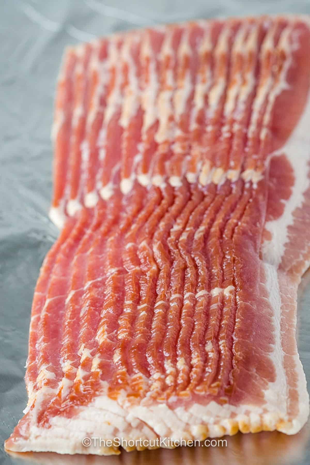 Brown sugar bacon adds a touch of sweetness to one of the most loved breakfast foods. The brown sugar caramelizes over the bacon, creating a crisp, flavorful coating that makes each slice extra delicious. This easy candied bacon pairs perfectly with eggs, pancakes, waffles, and French toast. Serve it at brunch or alongside a special holiday breakfast for a crowd-pleasing side. Make a batch today. #theshortcutkitchen a pound of bacon, unprepared, to make brown sugar bacon.